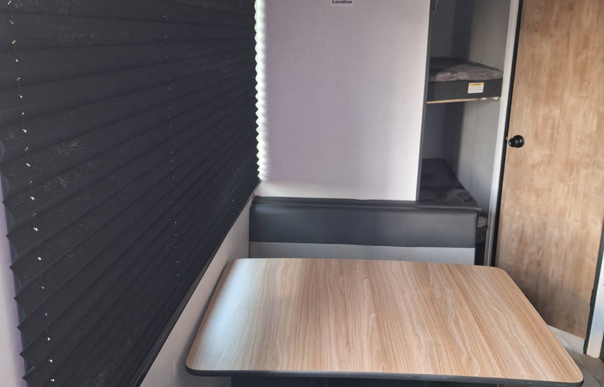 Inside an RV rental, featuring a dinette table, bunk beds, and dark window blinds.. Keystone RV Springdale 2023