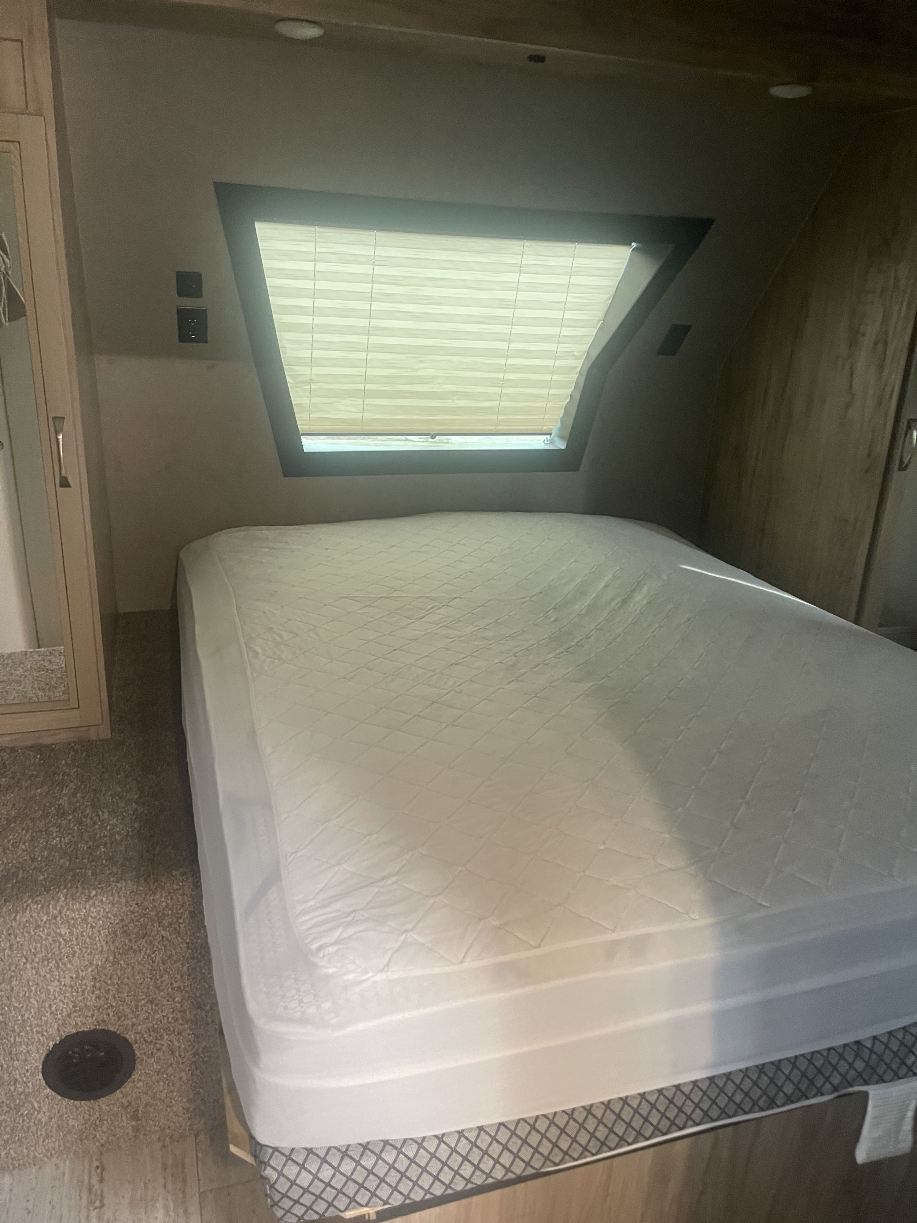 Cozy RV rental bedroom with a large bed, quilted mattress protector, and sloped window with blinds. Includes convenient wall outlets.. Palomino Solaire Ultra Lite 2020
