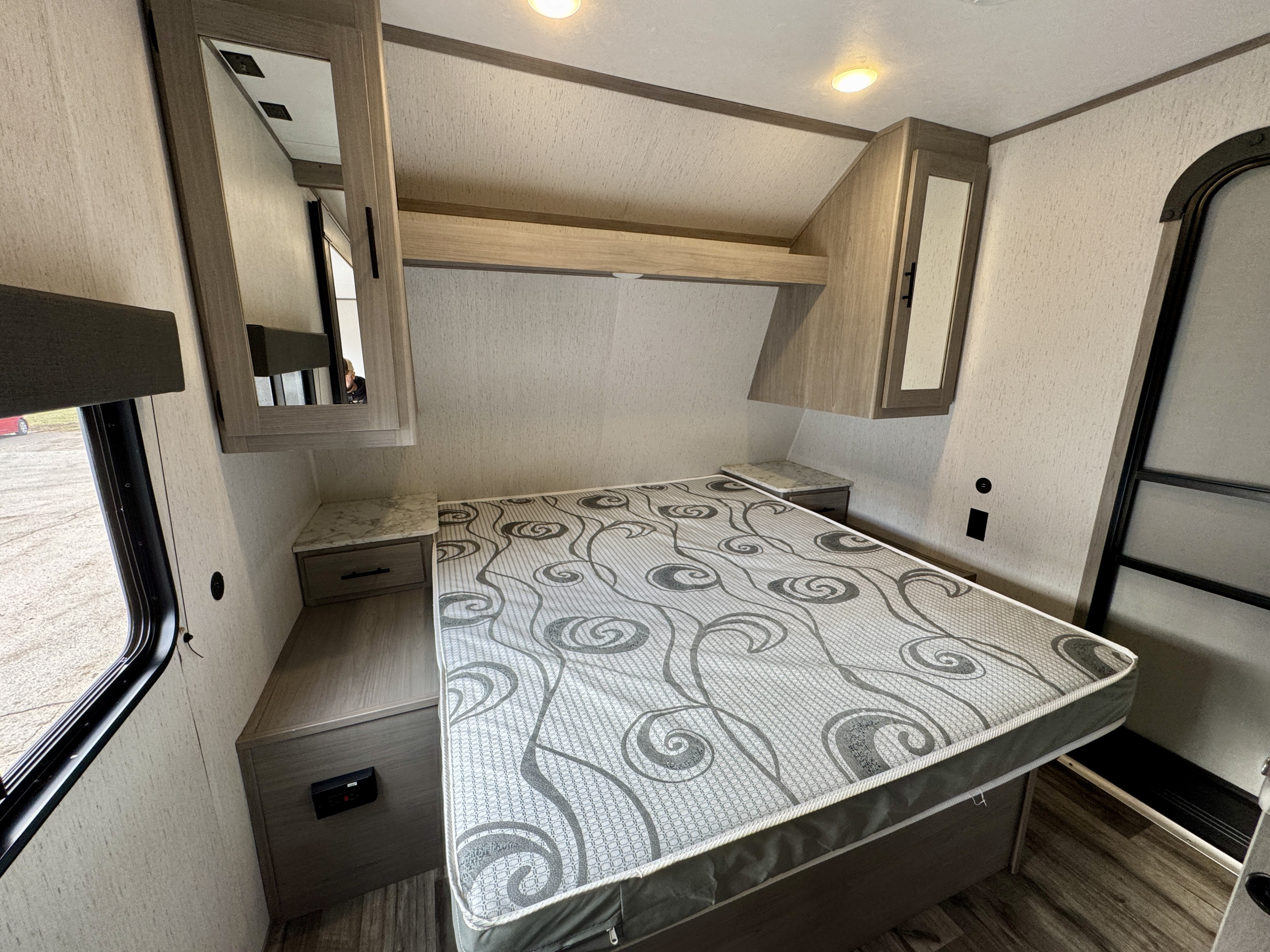 Experience comfort in this RV rental bedroom: features a patterned mattress, nightstands, and overhead storage.. Coleman Lantern 2022