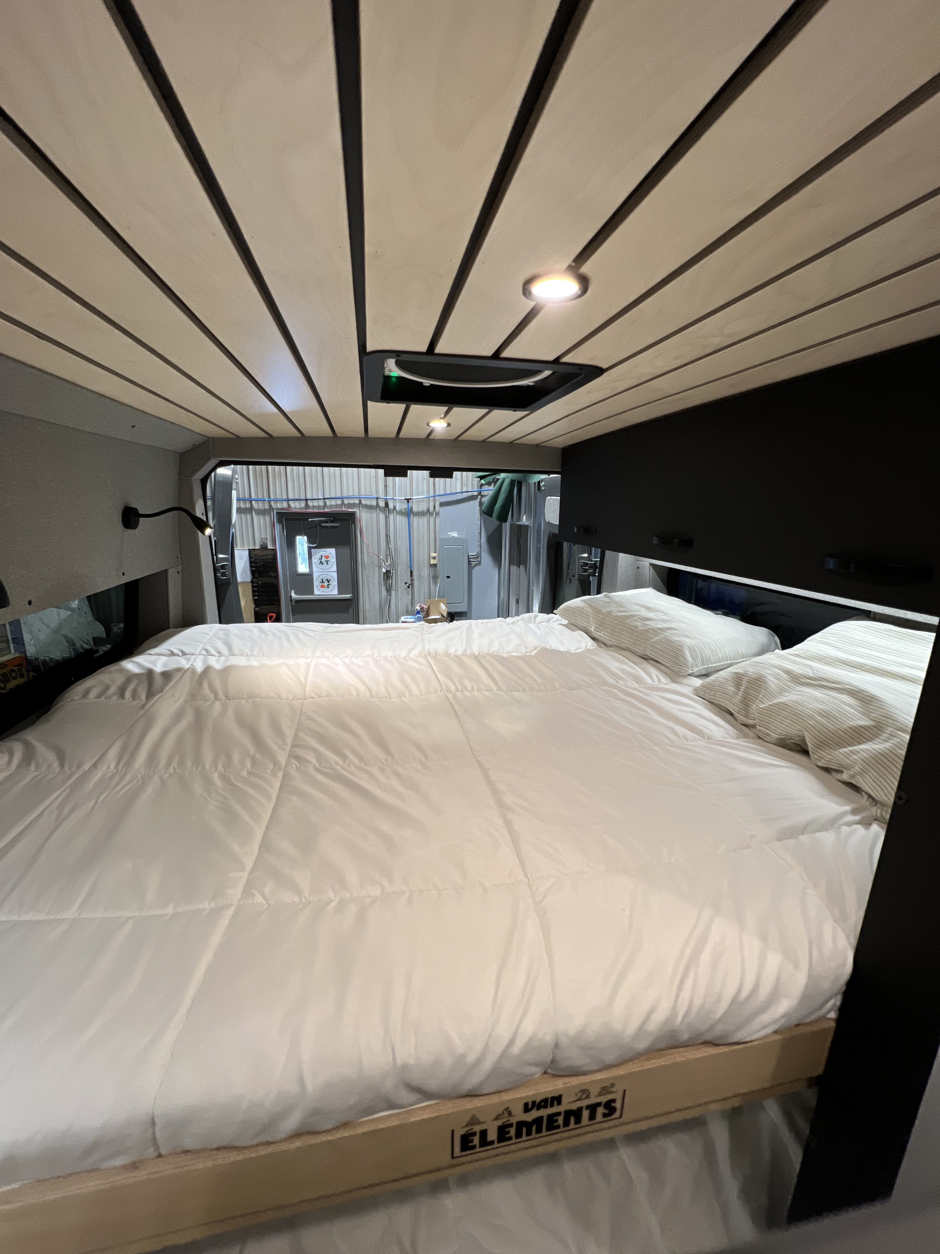 This RV rental features a cozy sleeping area with a comfortable bed, wood-slat ceiling, and practical overhead storage.. Dodge Sportsman 2022
