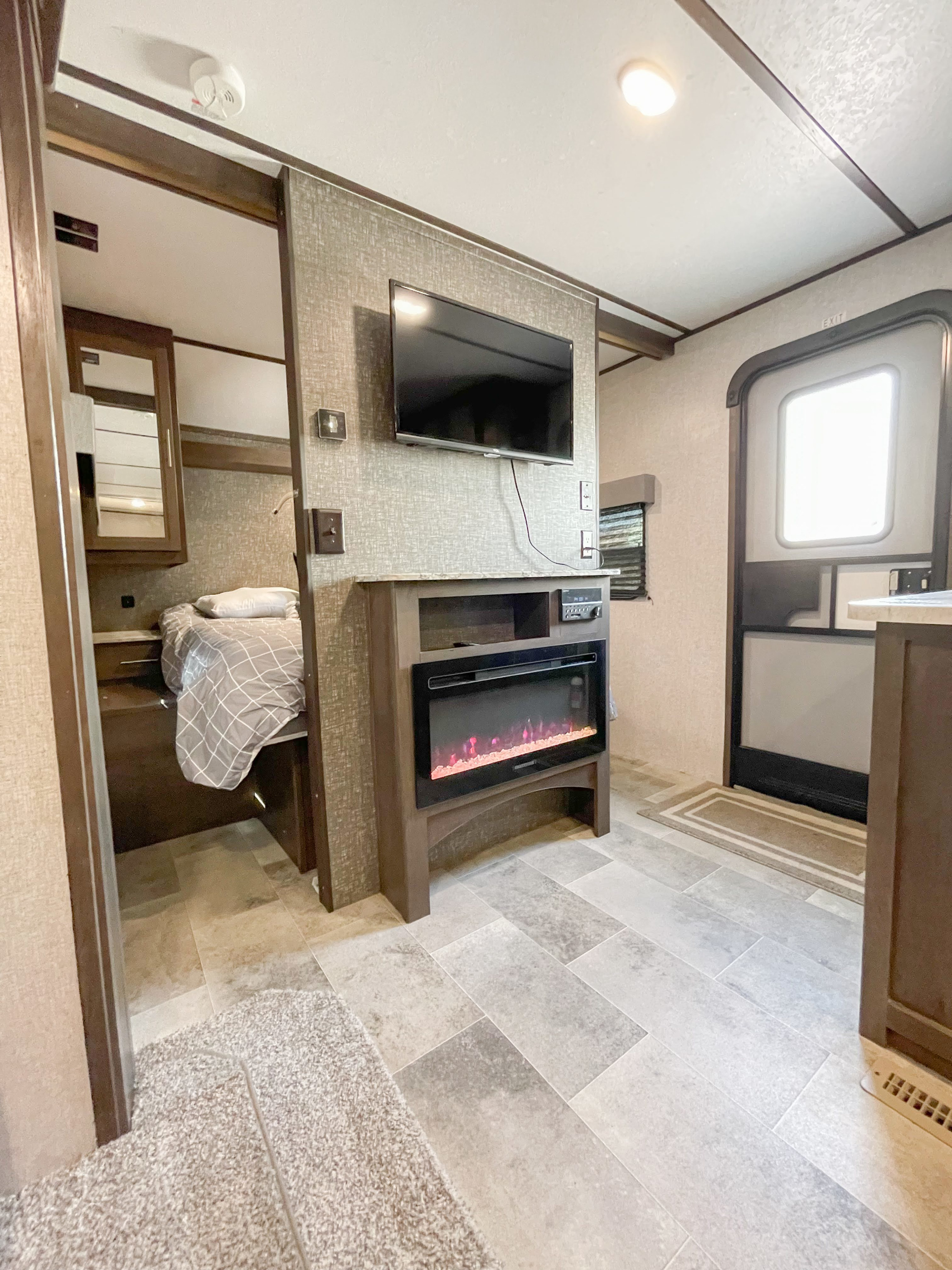 Spacious RV rental interior featuring a cozy bedroom, electric fireplace, and mounted TV.. Dutchmen Coleman 2020