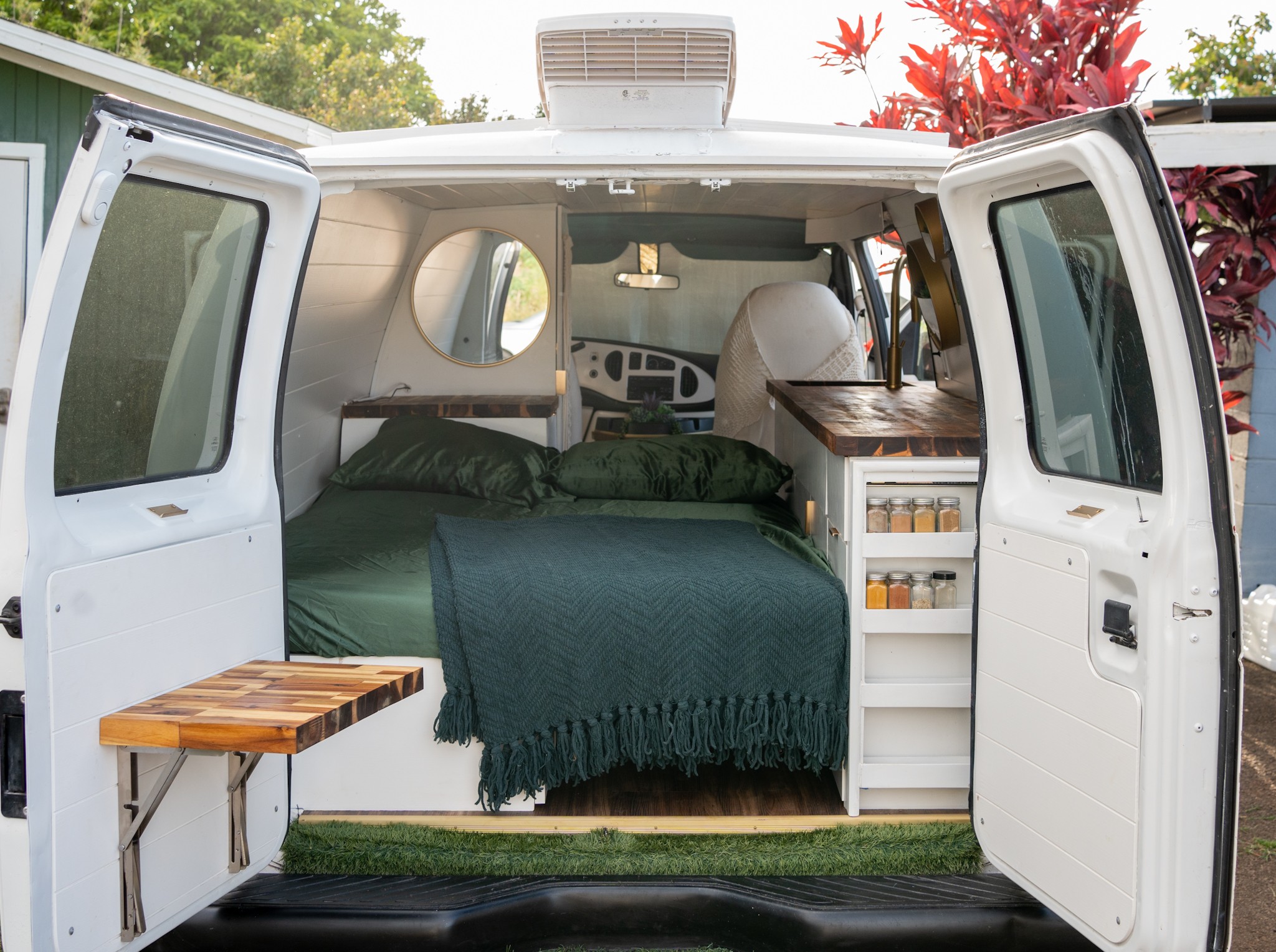 Inside an RV rental camper van: a bed with green bedding, wooden counter kitchen, and folding table. Ready for adventures.. Ford Econoline 2006