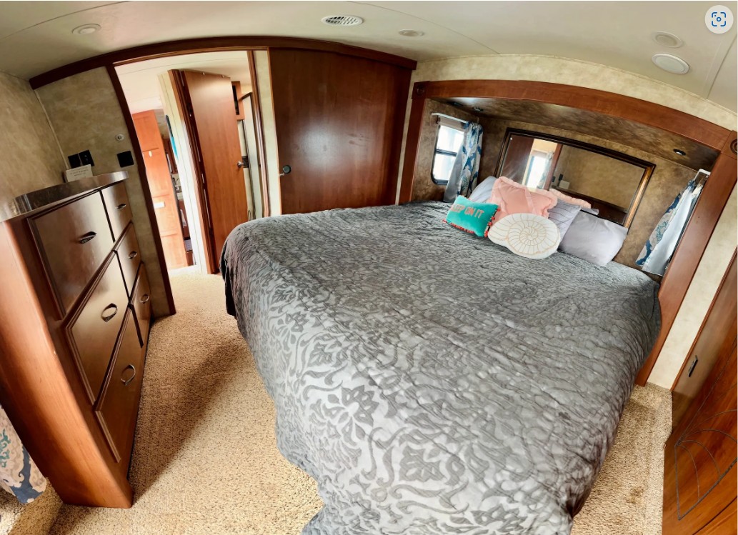 Explore this cozy RV rental bedroom. Plush bed, dresser, and private bath access make it a comfortable home on wheels.. Forest River Sandpiper 2012