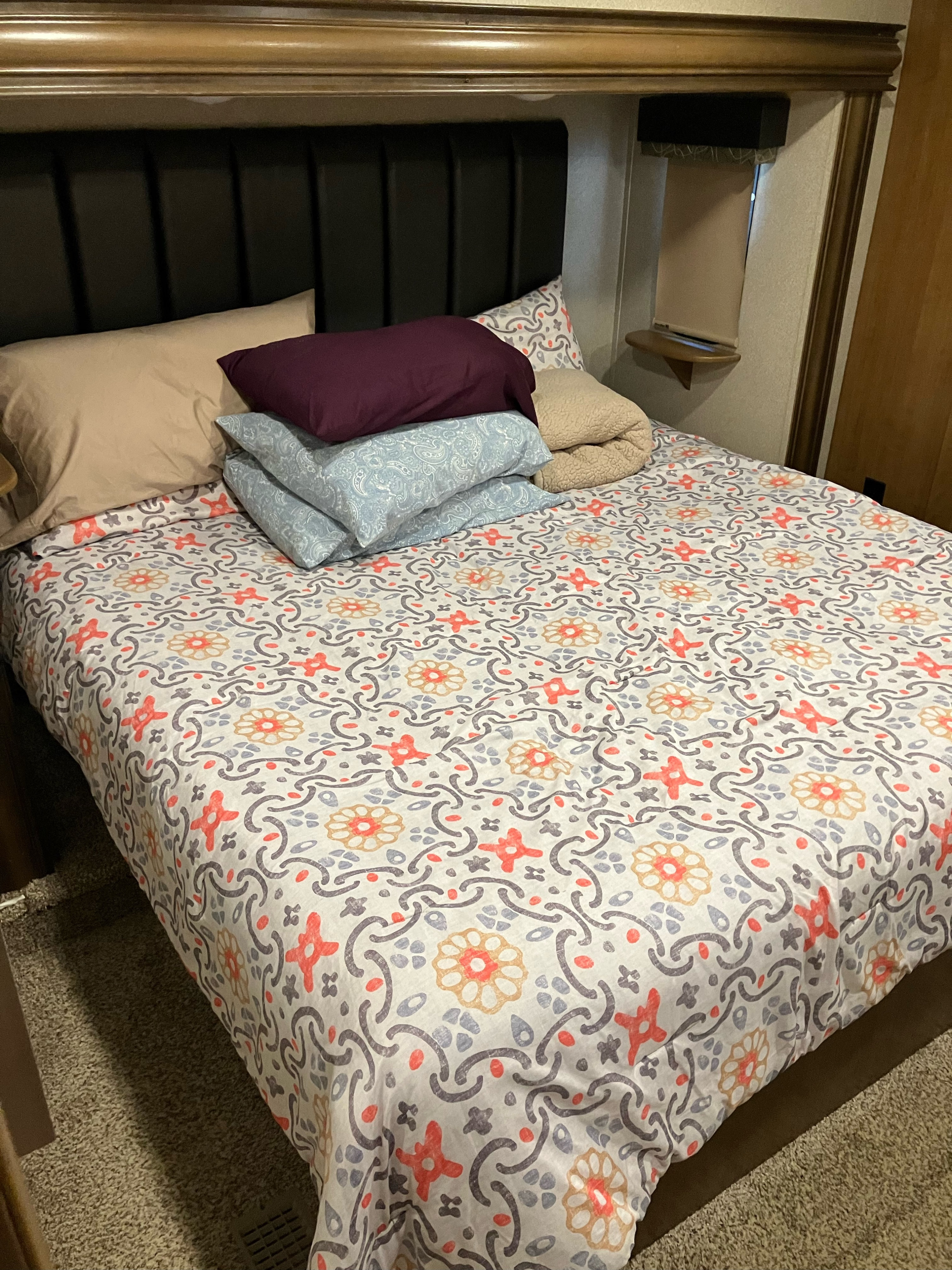 Cozy RV rental bedroom features a comfy bed with decorative patterned bedding and stacked pillows.. Cedar Creek Hathaway 2018