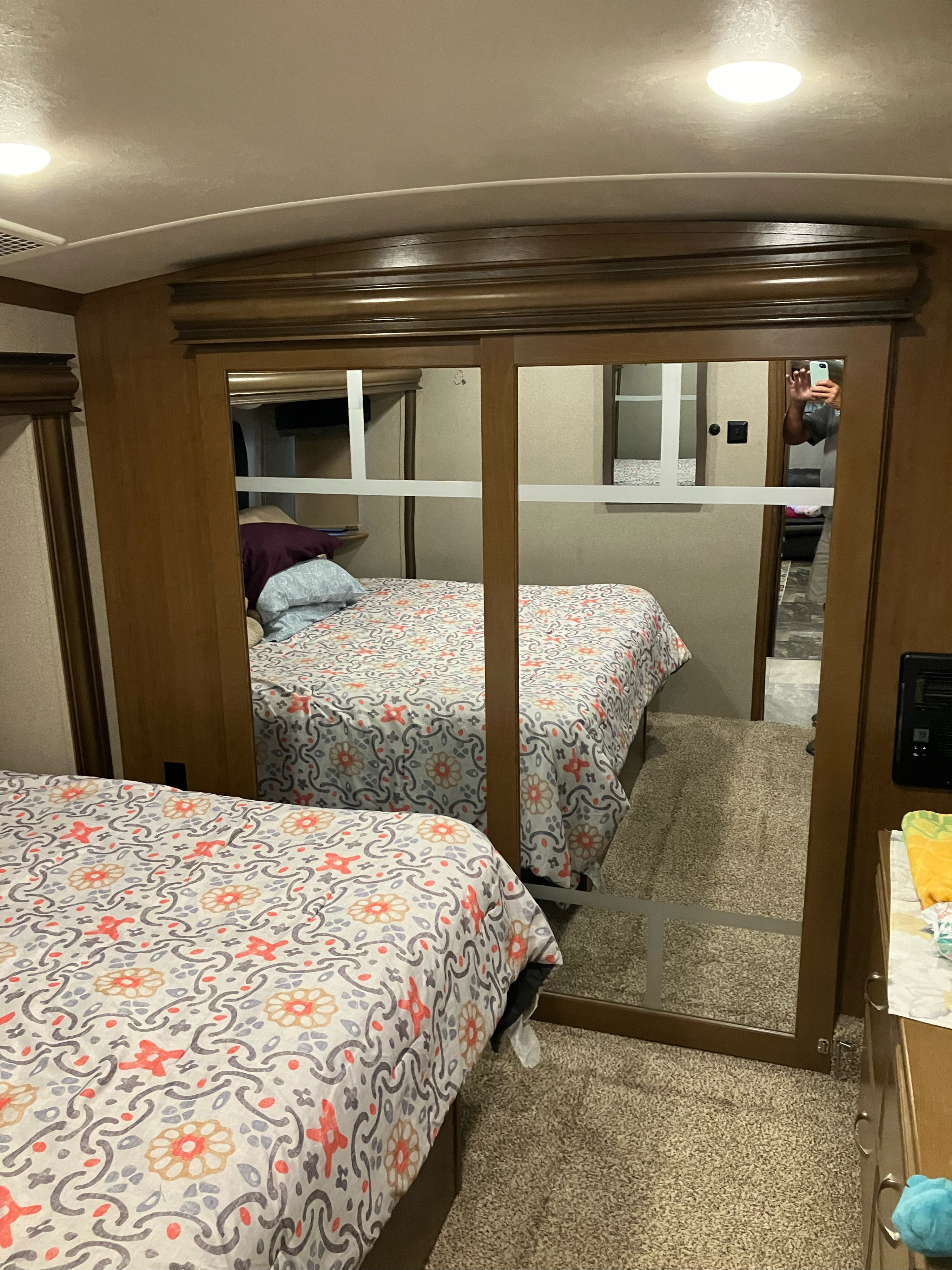 RV rental bedroom featuring a patterned comforter, mirrored closet doors, and soft carpet flooring.. Cedar Creek Hathaway 2018