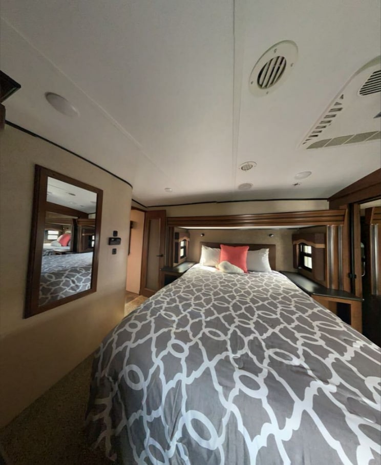 This RV rental features a cozy bedroom with a comfortable bed, built-in storage, and modern styling.. Jayco North Point 2016