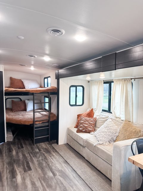 This RV rental interior features modern bunk beds and a cozy sofa with throw pillows, creating a comfortable living space.. Keystone RV Passport GT 2022