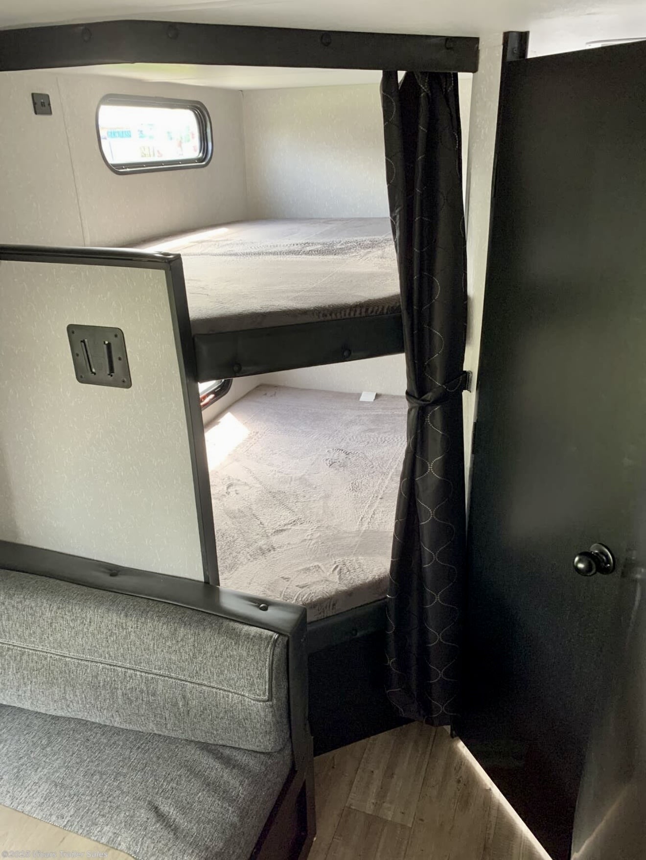 Bunk beds, a sofa, and a curtained doorway inside an RV rental. Ideal for family adventures in a travel trailer.. Forest River Cherokee Grey Wolf 2022