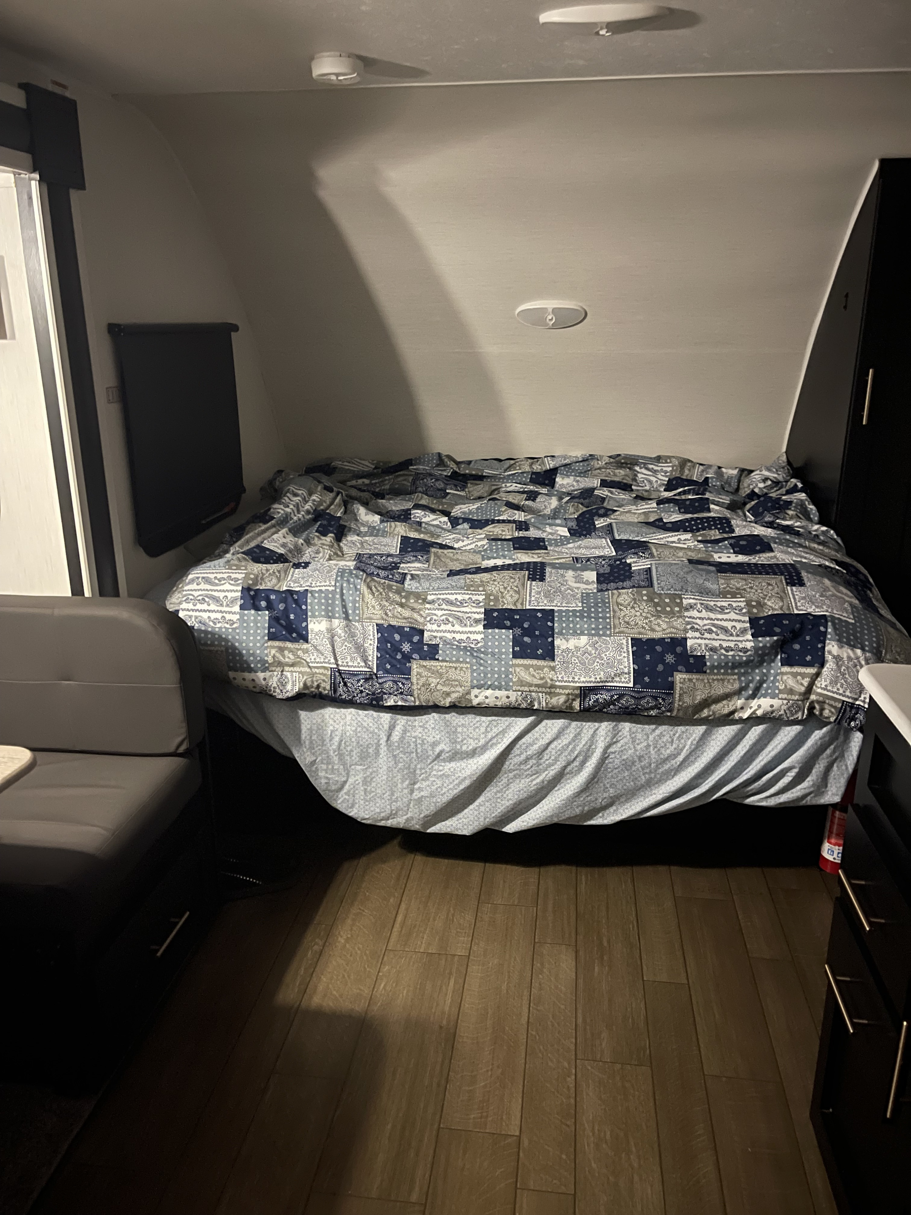 Cozy RV rental bedroom with patterned bed, compact dining, and wood floor, perfect for travel.. Forest River Wildcat 2022