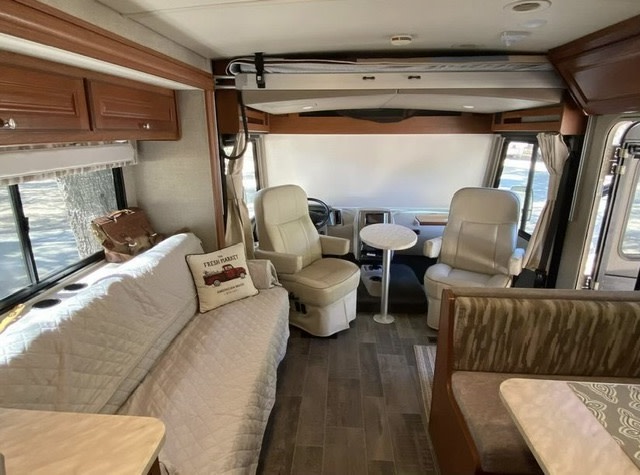 Spacious RV rental interior featuring a sofa, swiveling captain's chairs, and dining area. Perfect for travel adventures.. Winnebago Vista LX 2019
