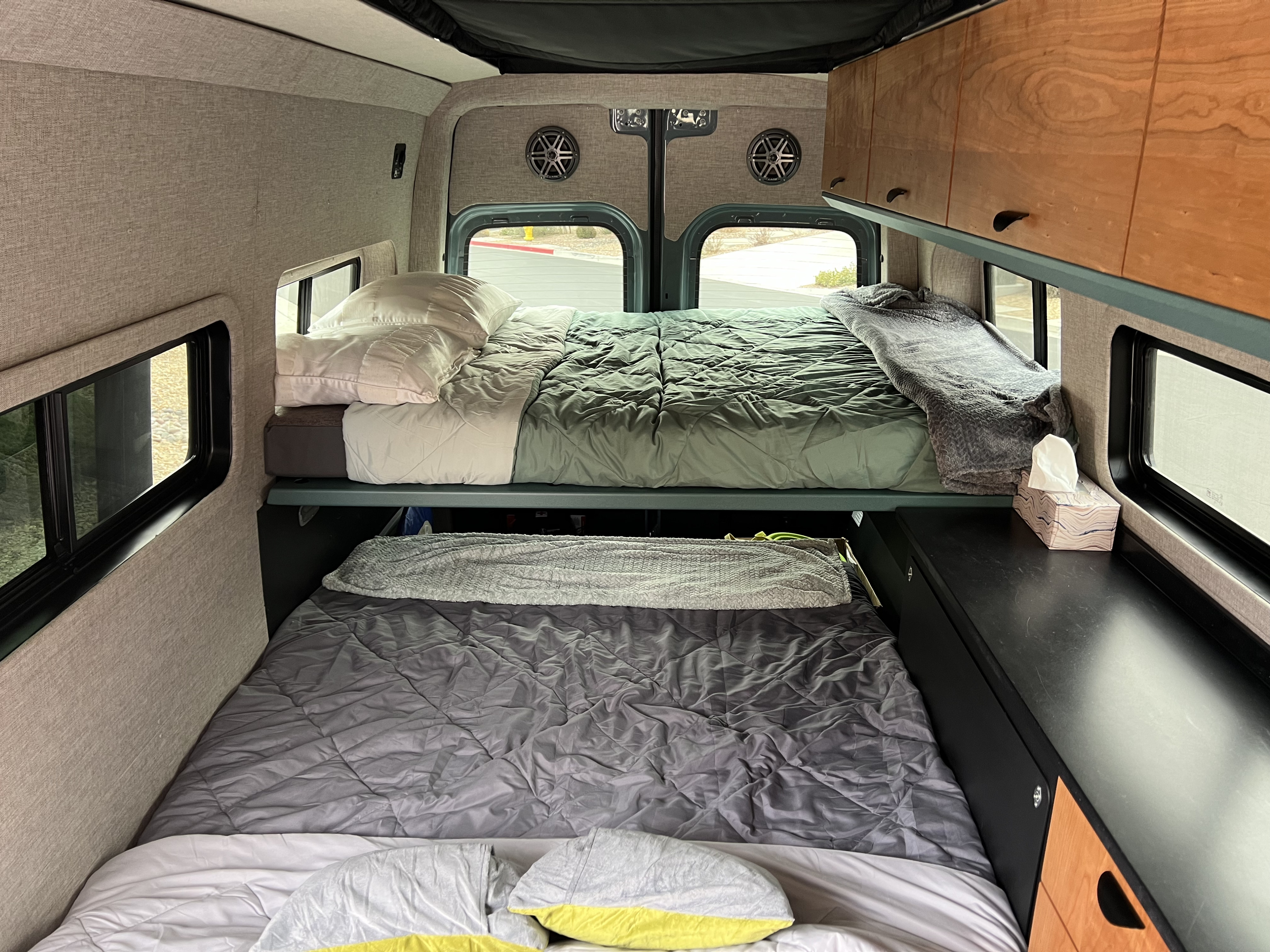 Stacked bunk beds inside an RV rental, featuring custom cabinetry and large windows for scenic views.. Off Highway Van Off Highway Van Class B 2024