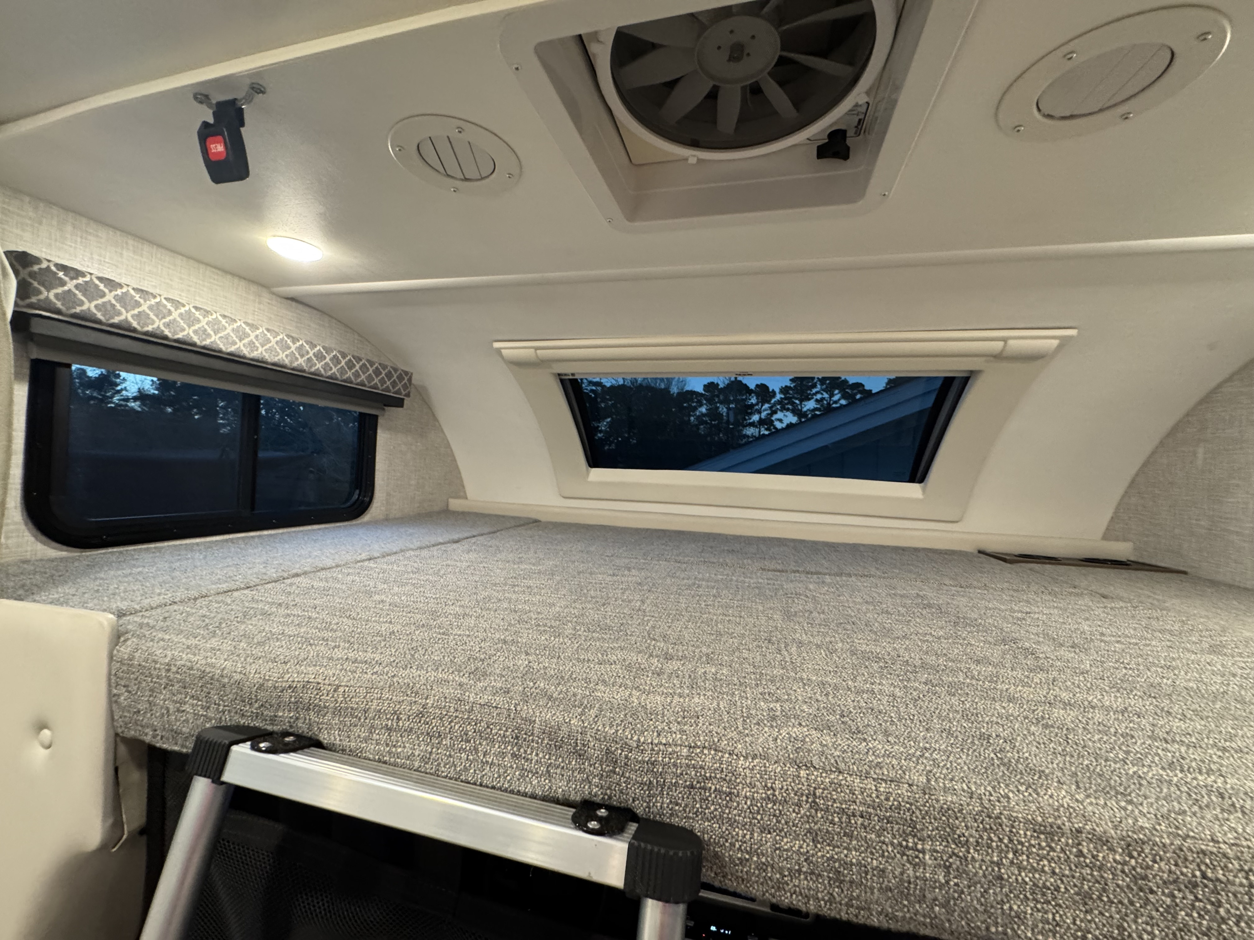 Experience comfort in this RV rental's spacious cab-over sleeping bunk, featuring windows, fan, vent, and access ladder.. Thor Quantum 2022