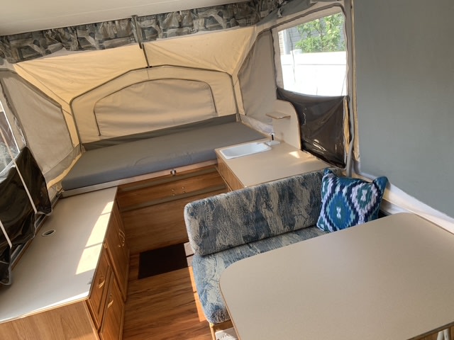 Pop-up camper RV rental interior with cozy bed, dinette, and compact kitchen. Spacious layout for your next adventure.. Palomino Pinto 1999