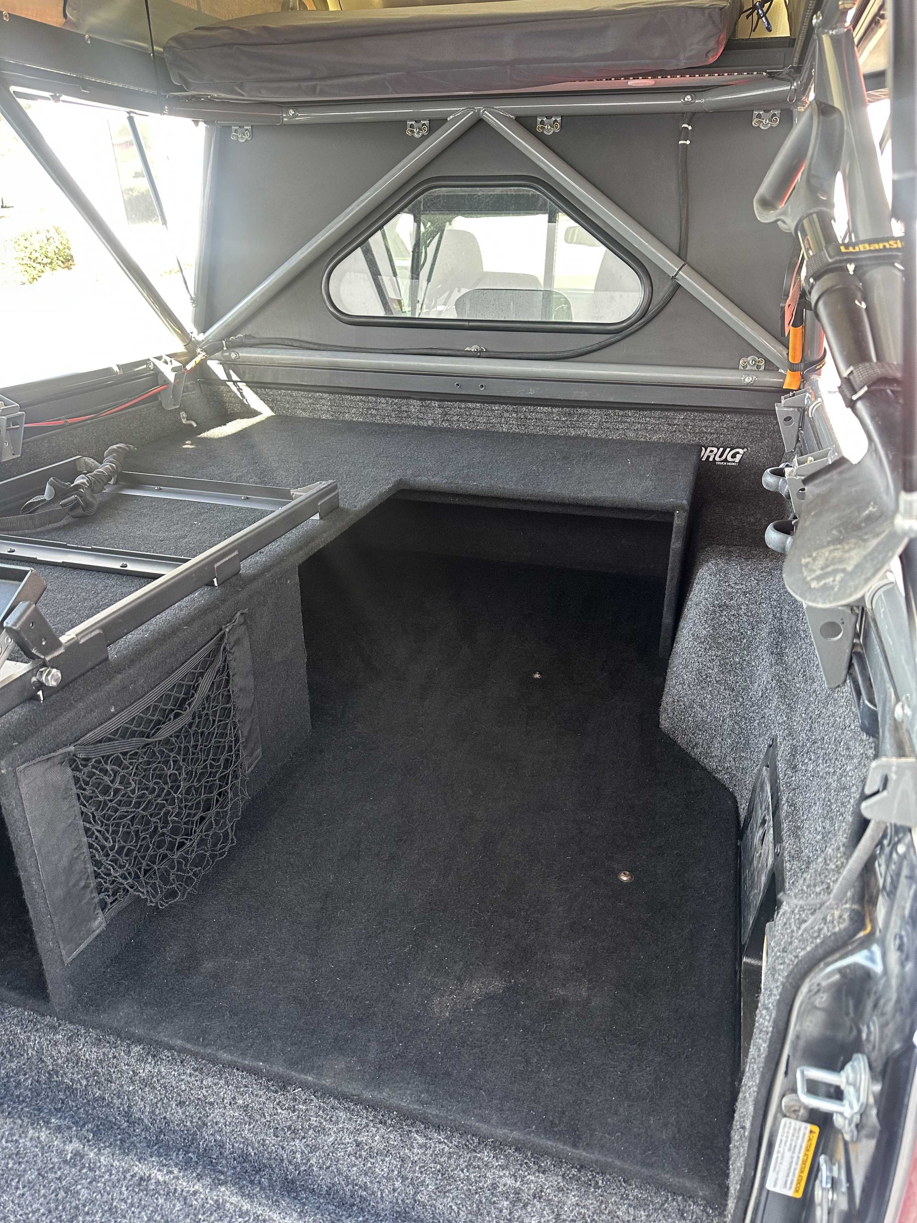 Carpeted truck bed interior with custom storage and topper, ready for your RV rental overlanding adventures.. 2023