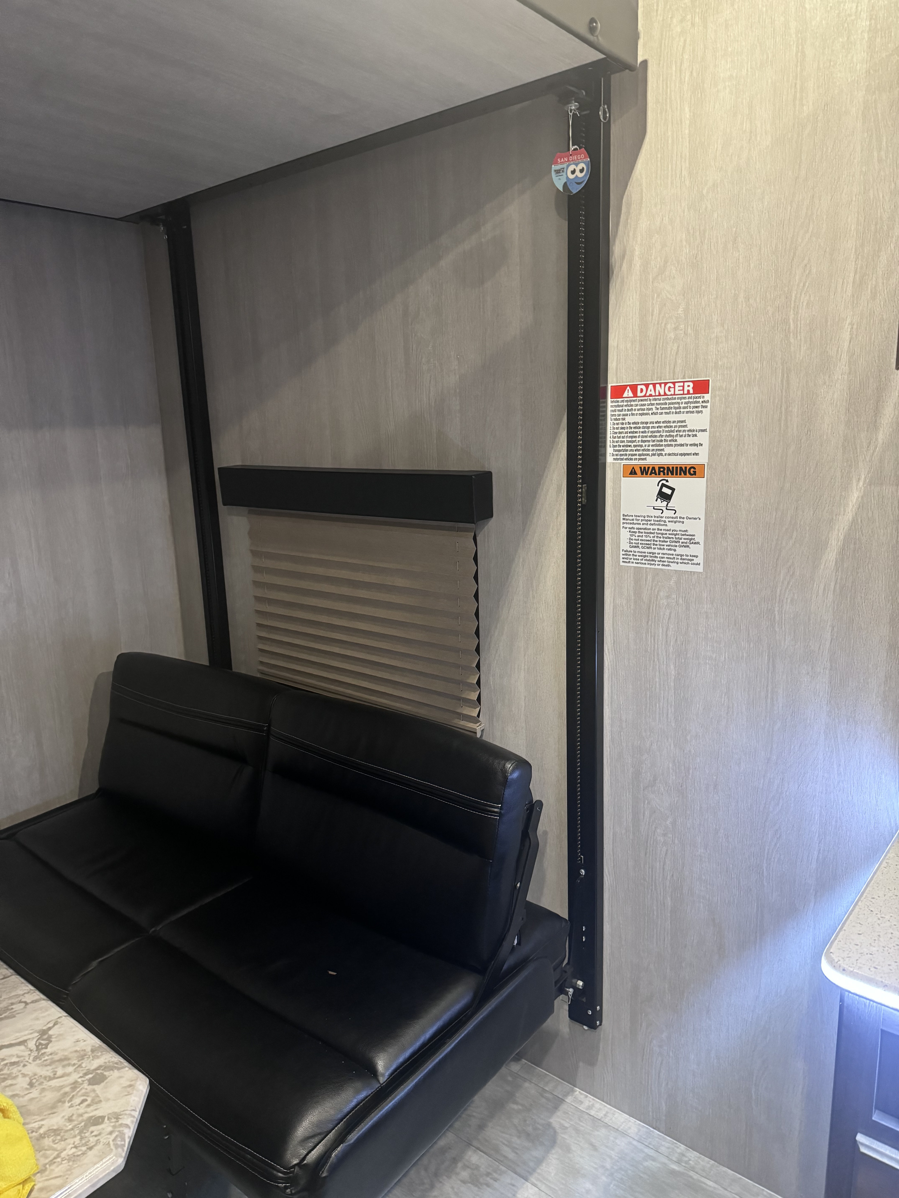 RV rental bunk bed and futon setup: modern interior with black seating, window blind, and essential safety warnings.. Genesis Supreme Rv Genesis Supreme 2022