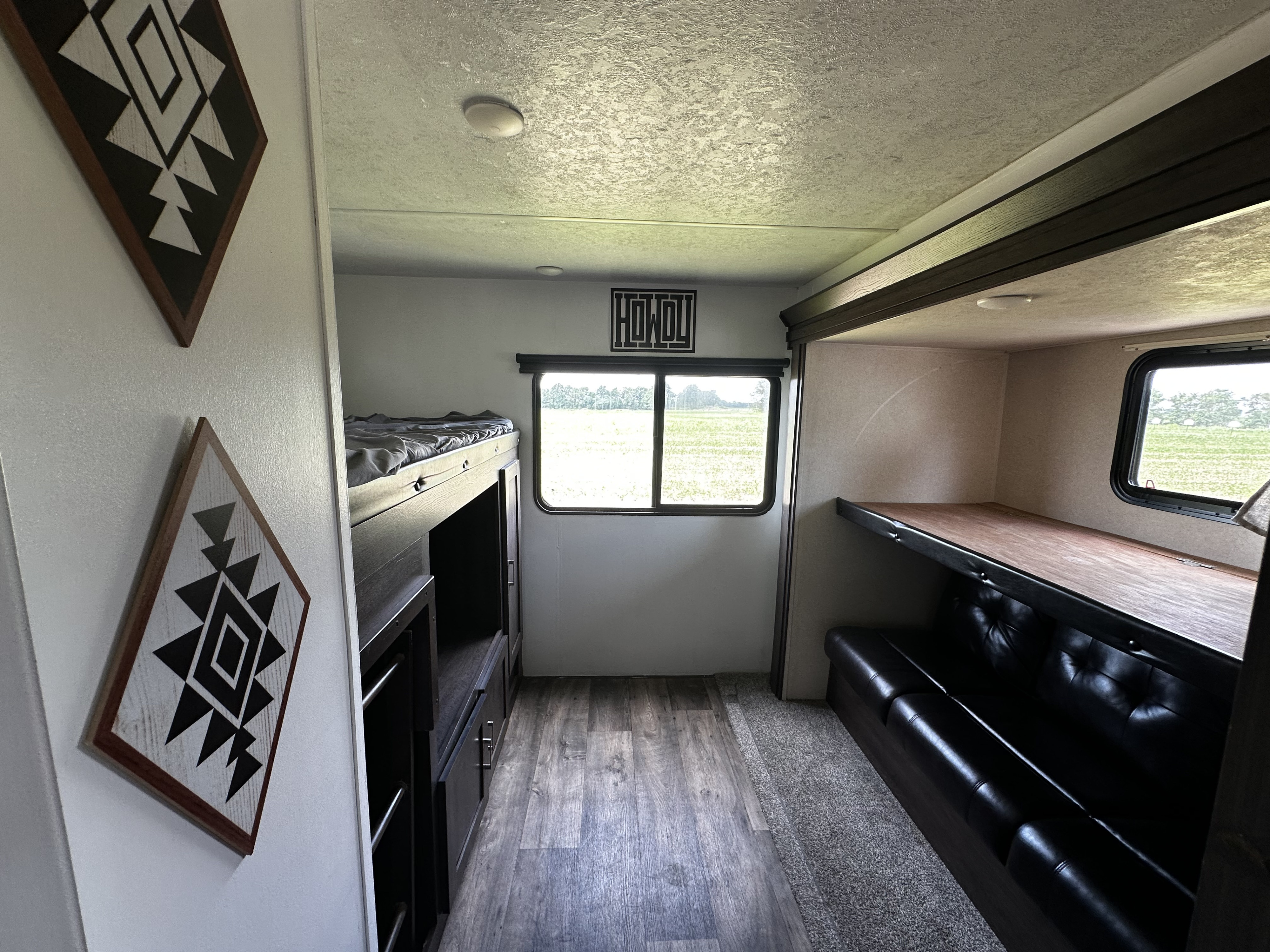 Spacious RV rental interior featuring bunk beds, a comfortable couch, and a large window overlooking a green field.. Forest River Wildwood 2018