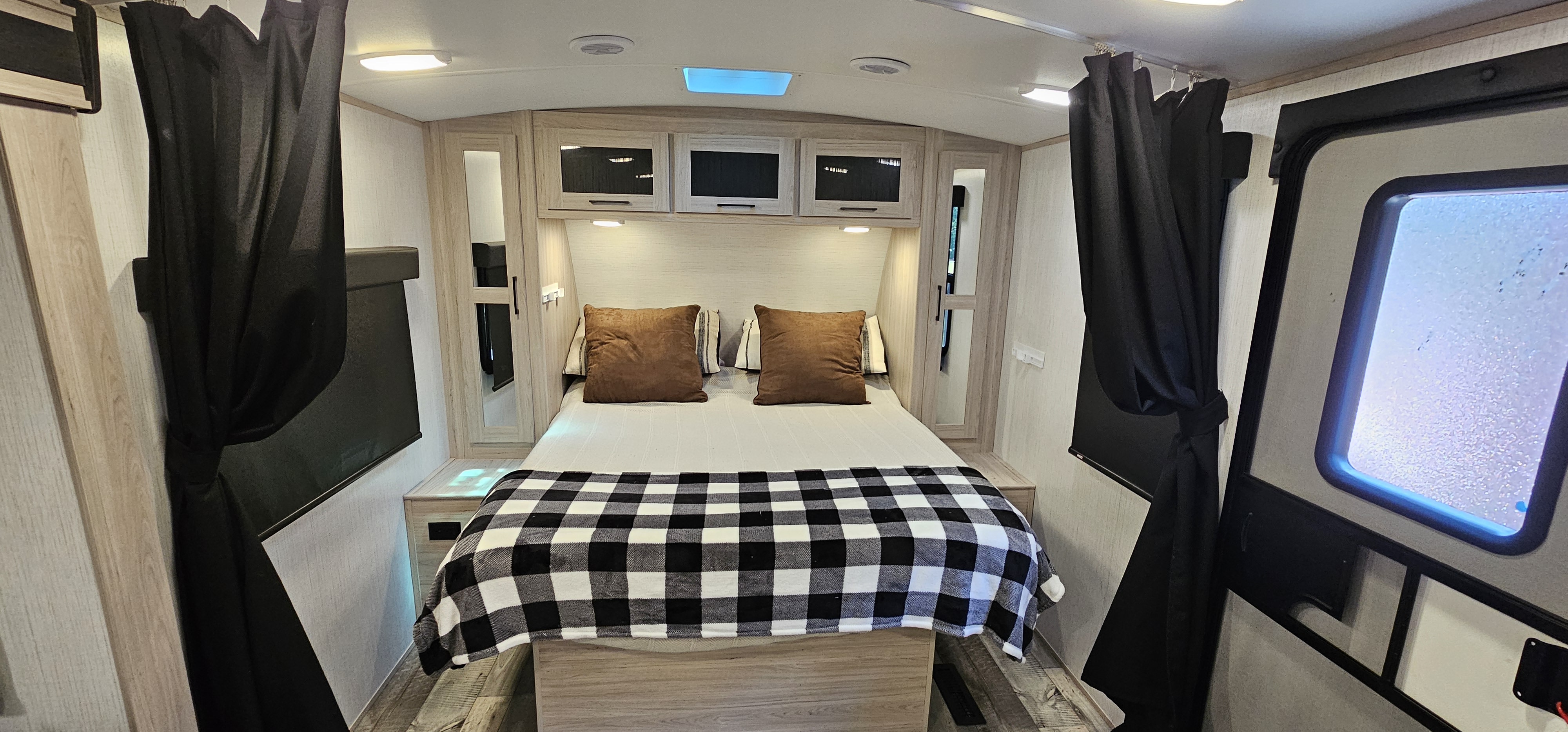 Enjoy a comfortable RV rental bedroom featuring a cozy bed, overhead storage, and privacy curtains.. Heartland RVs Sundance Ultra Lite 2022