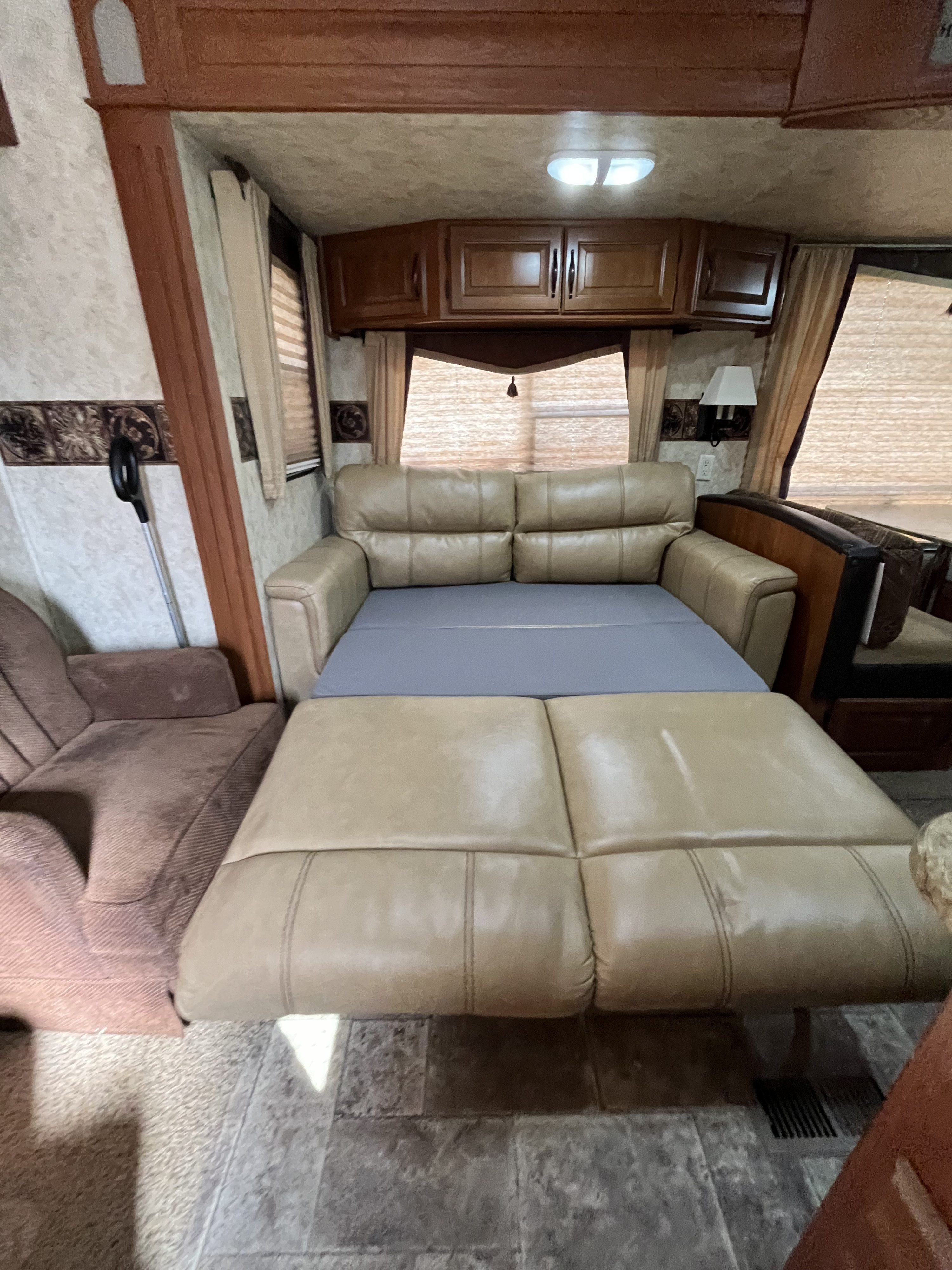 Spacious RV rental interior with a cozy sofa bed pulled out, perfect for a comfortable night's sleep.. Keystone RV Cougar 2011