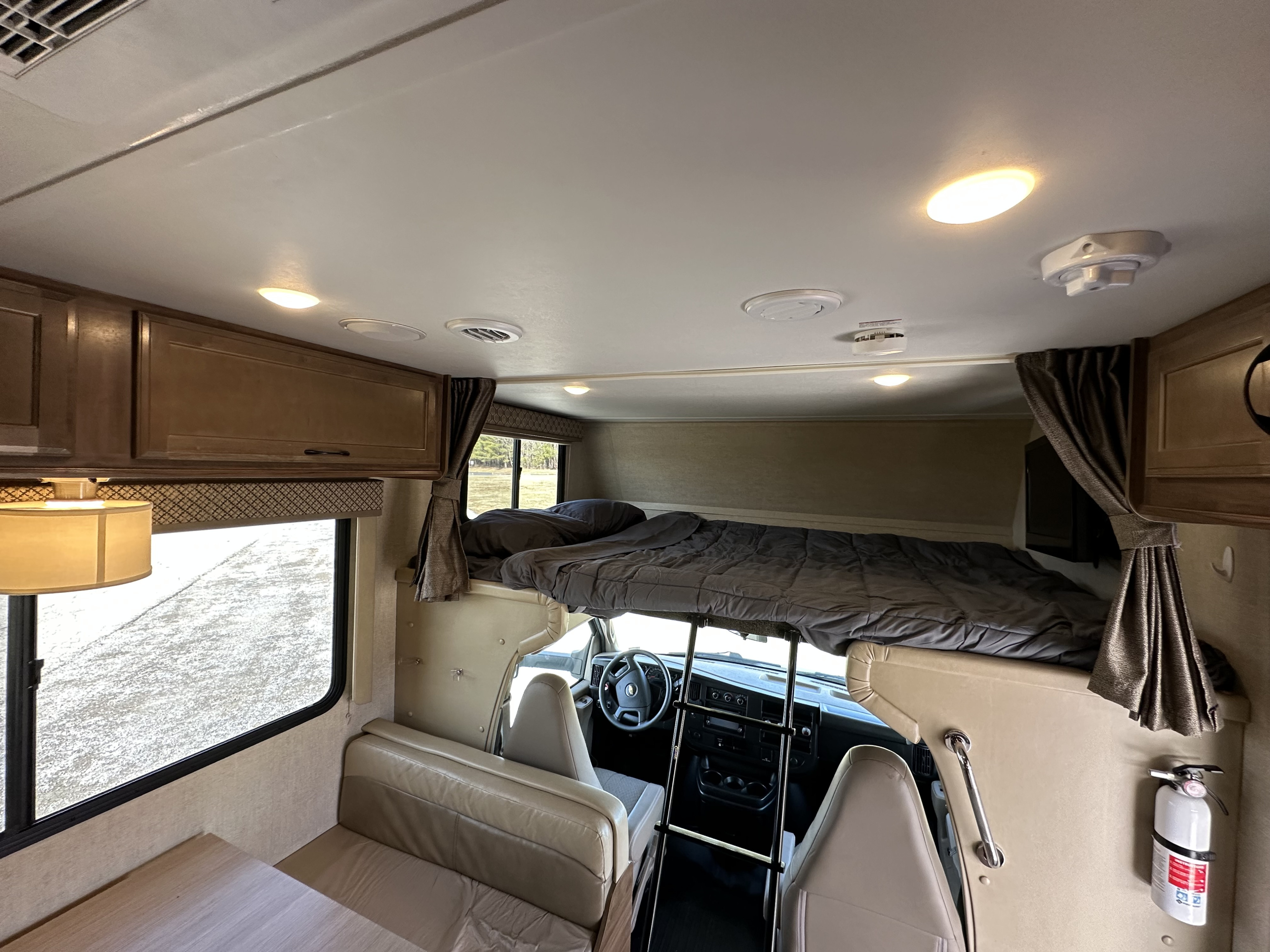 Spacious RV rental interior with over-cab bunk, dining area, and driver's cab. Features include lights, vents, and safety equipment.. Gulf Stream Conquest 2018