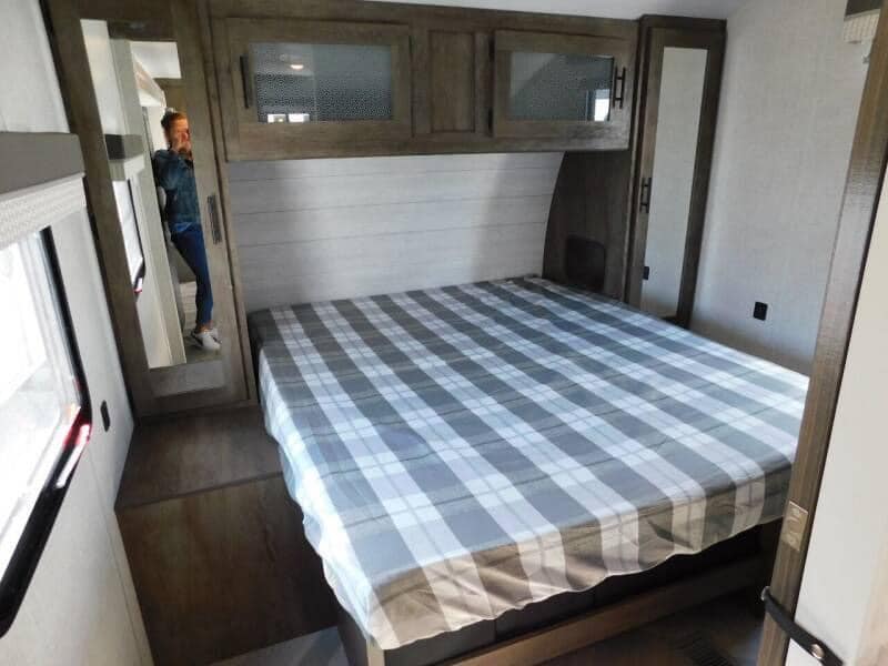 Comfortable RV rental bedroom with plaid bed, overhead storage, and mirror. Perfect for your next adventure!. FOREST RIVER 22RBS 2021