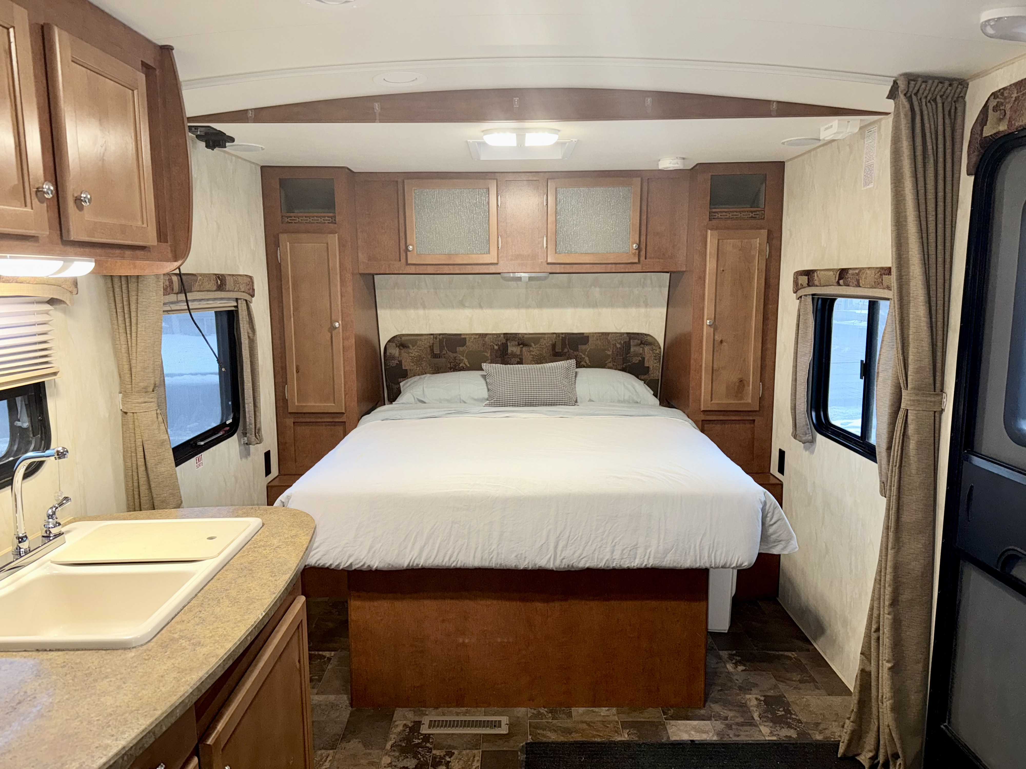 View inside an RV rental: a comfortable bedroom with a full bed, overhead and side storage, plus a kitchen sink.. Nash Nash Trailer 2016