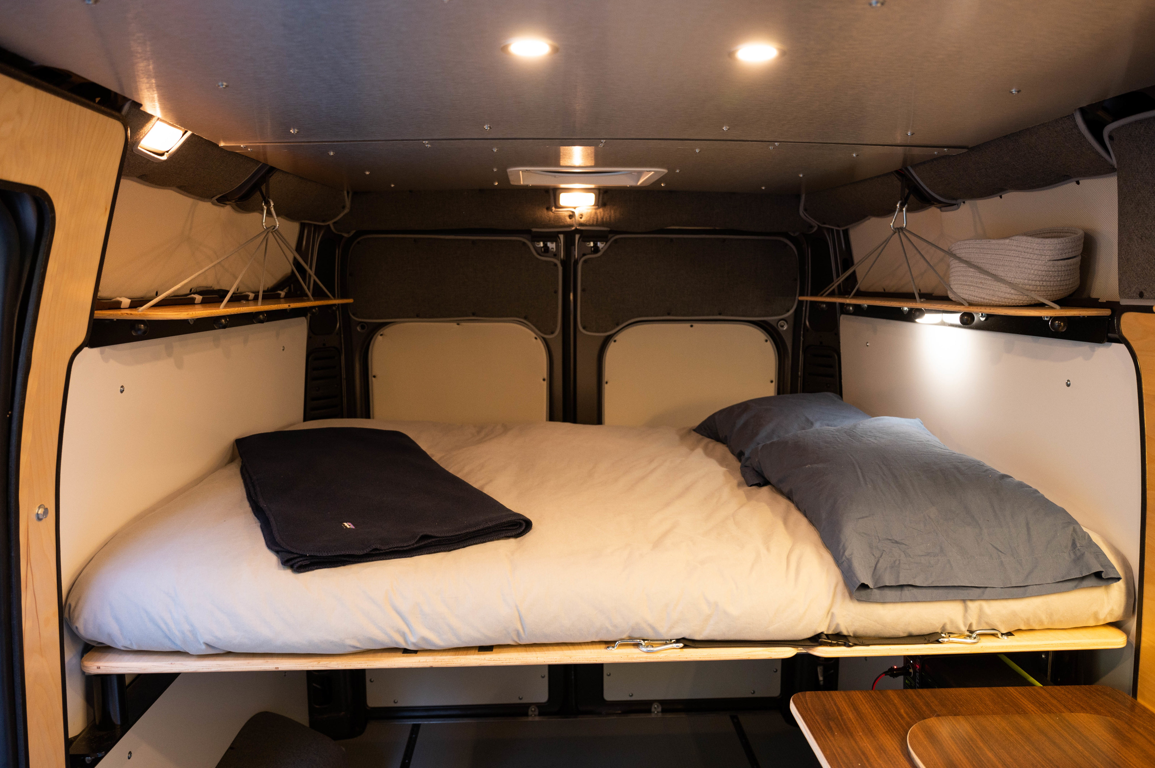Discover this well-appointed RV rental's sleeping area, featuring a comfortable bed, multiple lighting options, and smart storage.. Dodge Promaster 2021