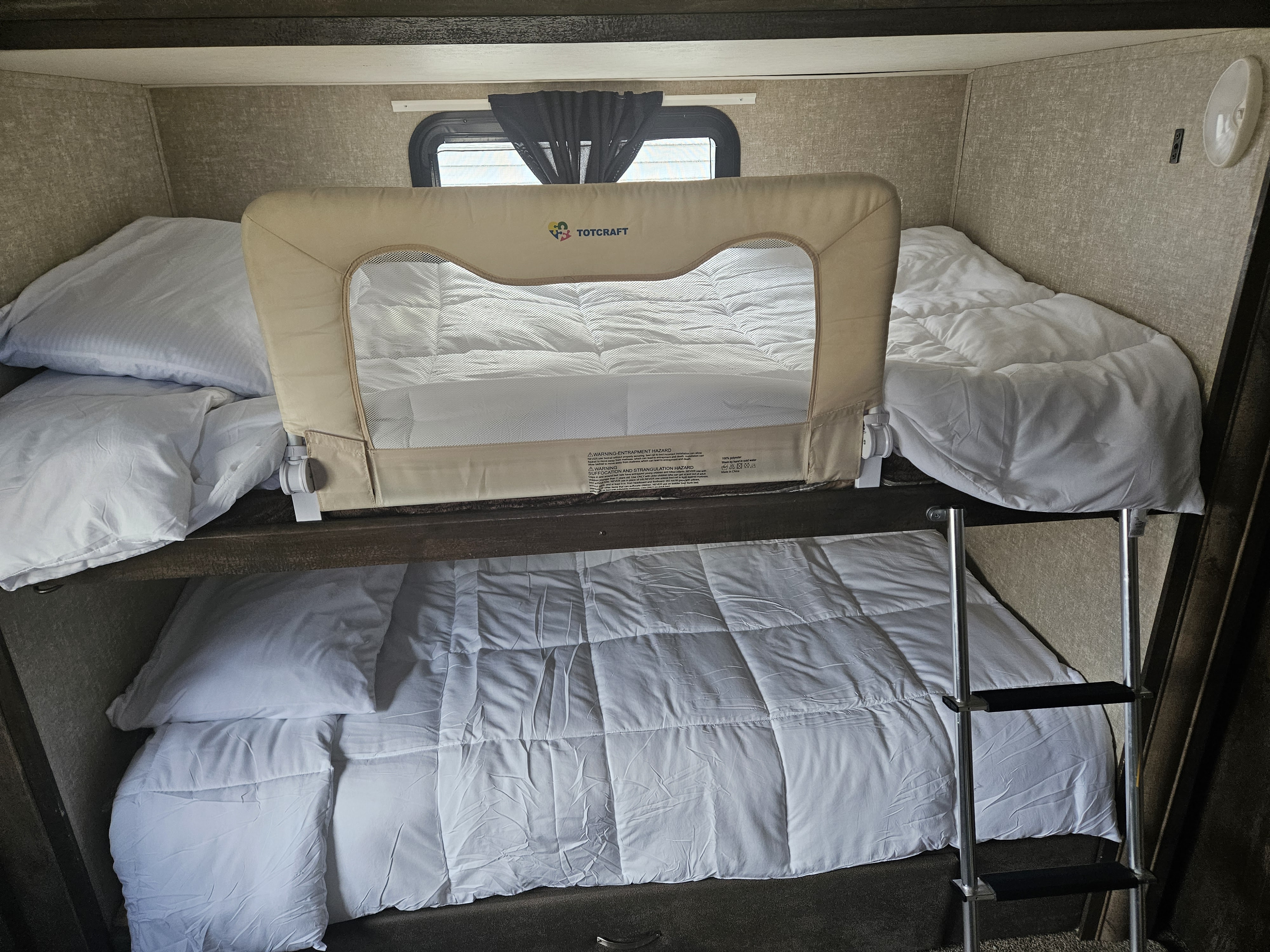 Inside an RV rental: cozy bunk beds with white linens and a child safety rail.. Forest River Vibe 2018