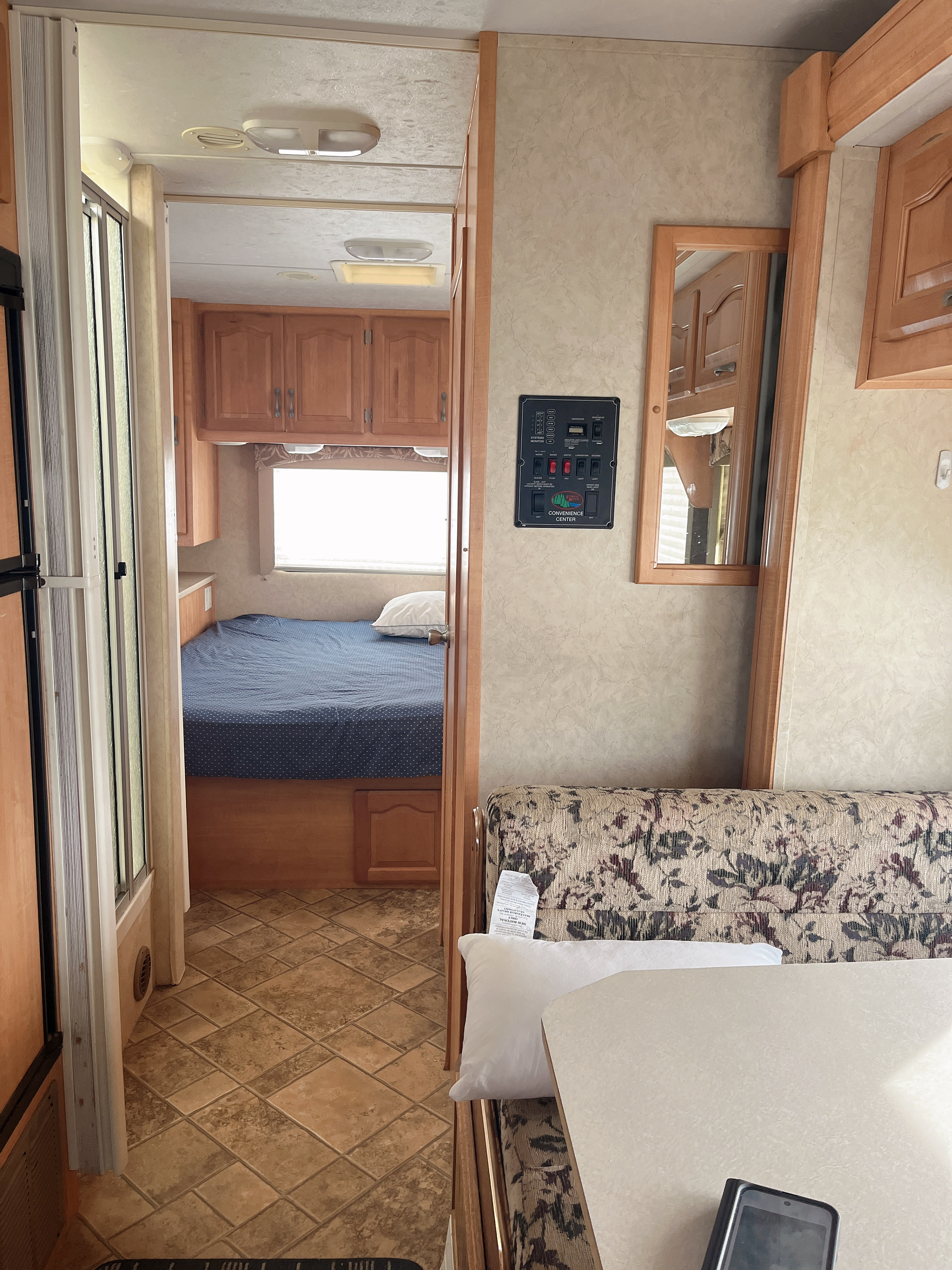 RV rental interior, featuring a bedroom, floral dinette, and central control panel. A functional mobile living space.. Forest River Sunseeker 2008
