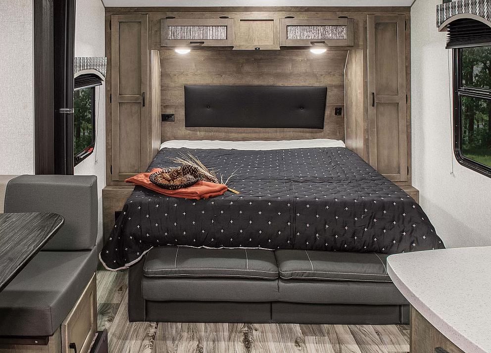 RV rental bedroom interior, showcasing a comfy bed, overhead cabinets, and dining area.. Sonic Sonic Trailer 2022