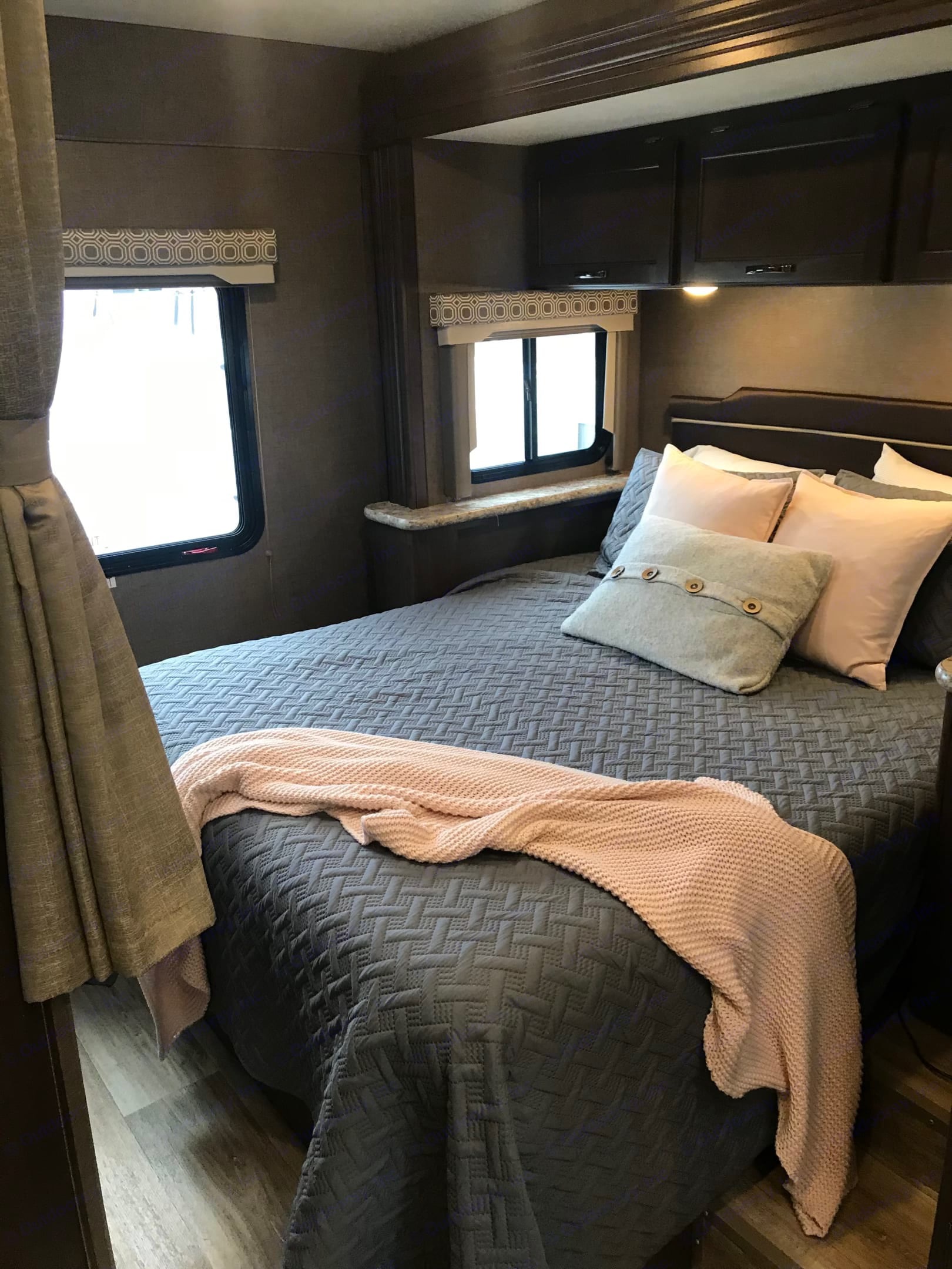 Experience comfort in this RV rental bedroom: quilted bed, throw blanket, overhead storage, & large windows.. Thor Four Winds 2019