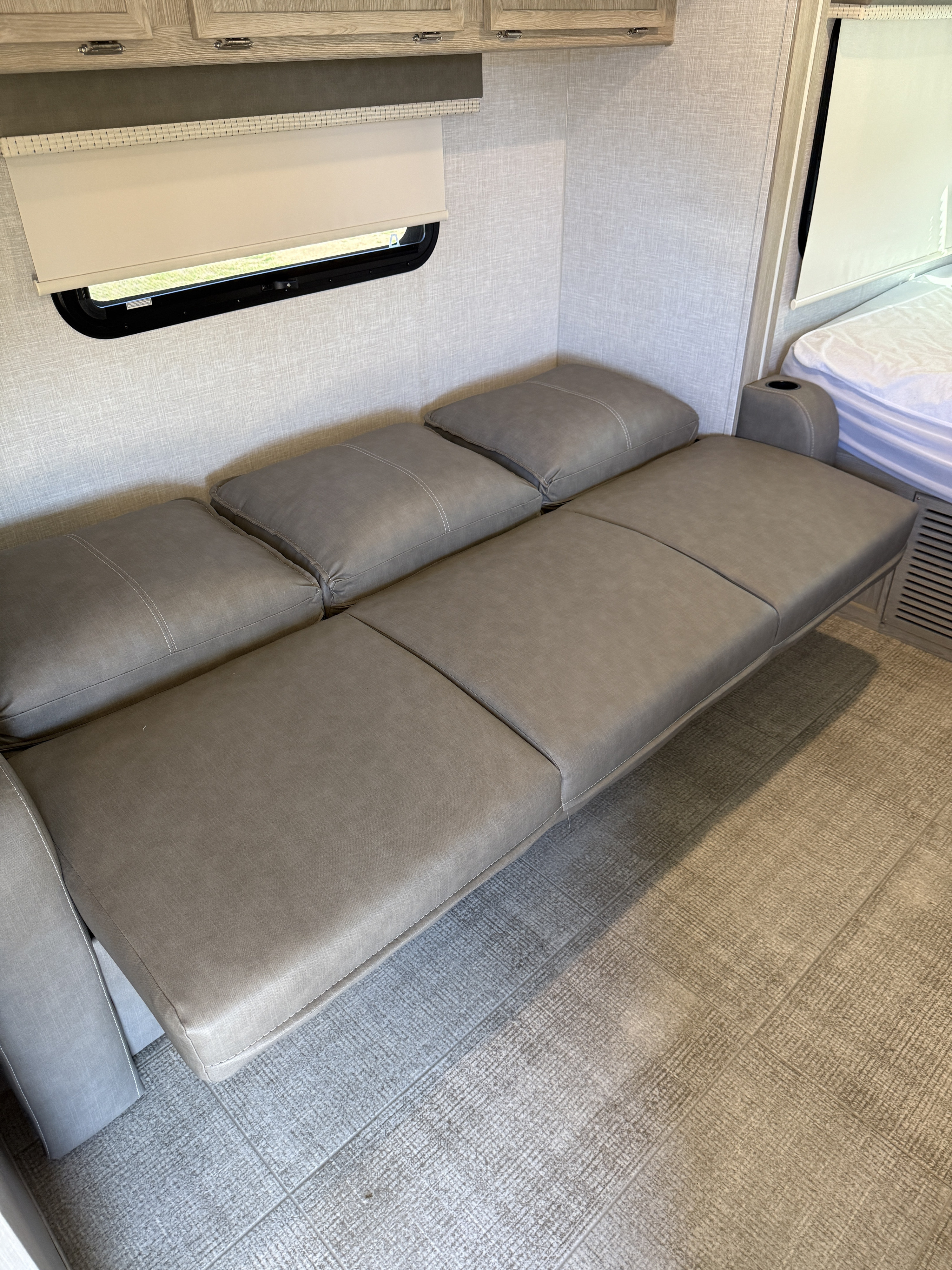 Modern RV rental interior: grey convertible sofa bed, window, cabinetry, and tile-look flooring.. Forks Rv Rockwood Geo Pro 2021