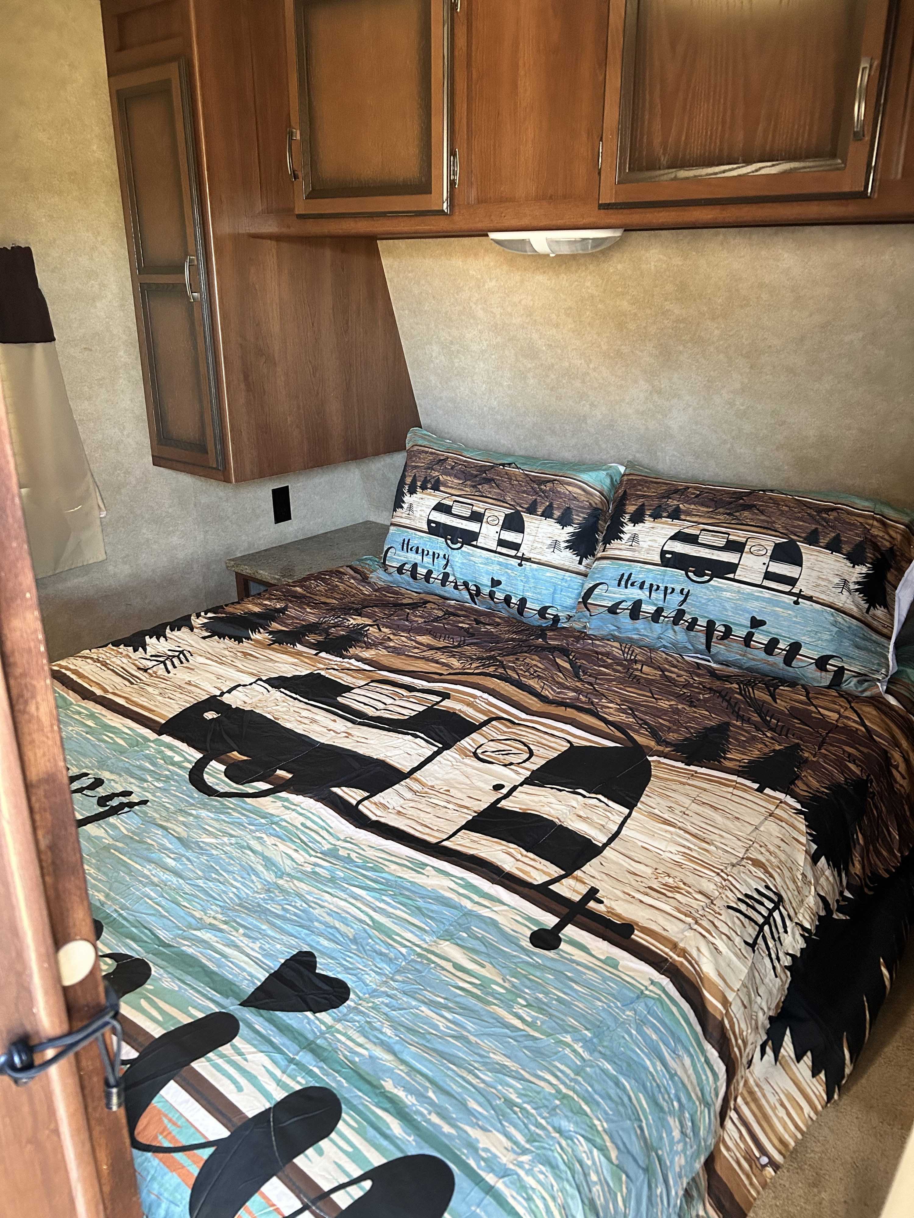 Cozy RV rental bedroom with camping-themed bedding and built-in storage.. Crossroads RV Zinger 2015