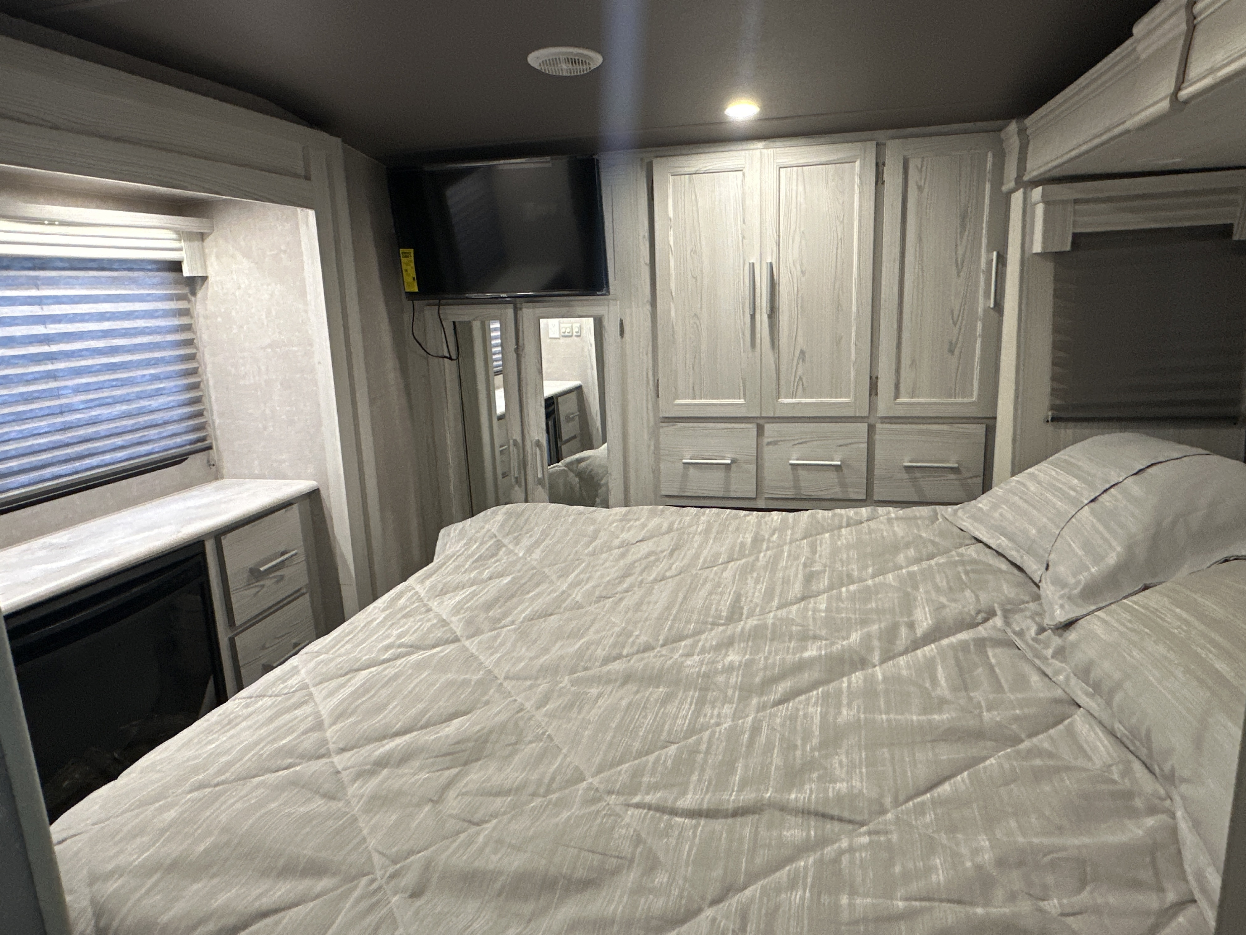 This cozy RV rental bedroom offers a bed, wall TV, built-in storage, window, and a fireplace for your travels.. Eclipse Recreational Vehicles Attitude 2023