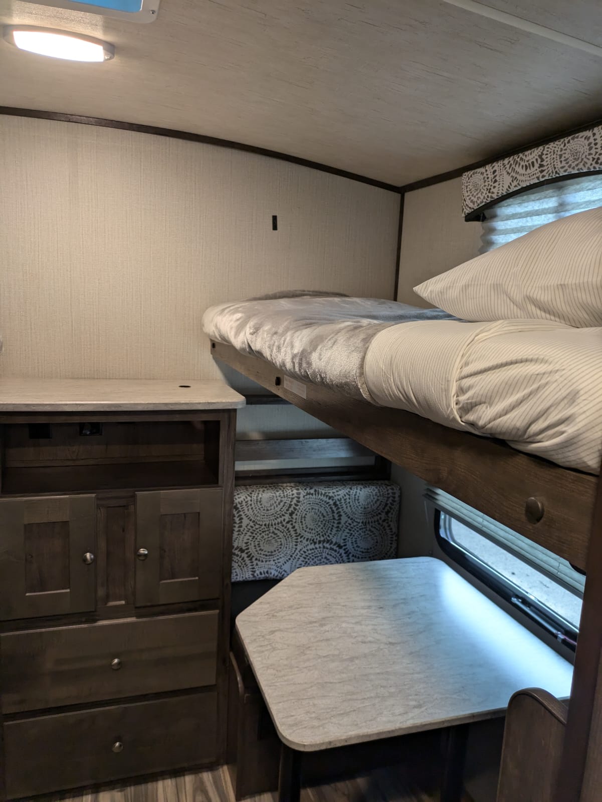 Compact RV rental interior with bunk beds, a dresser, and a dinette area featuring a small table.. Cruiser RV MPG Ultra Lite 2019