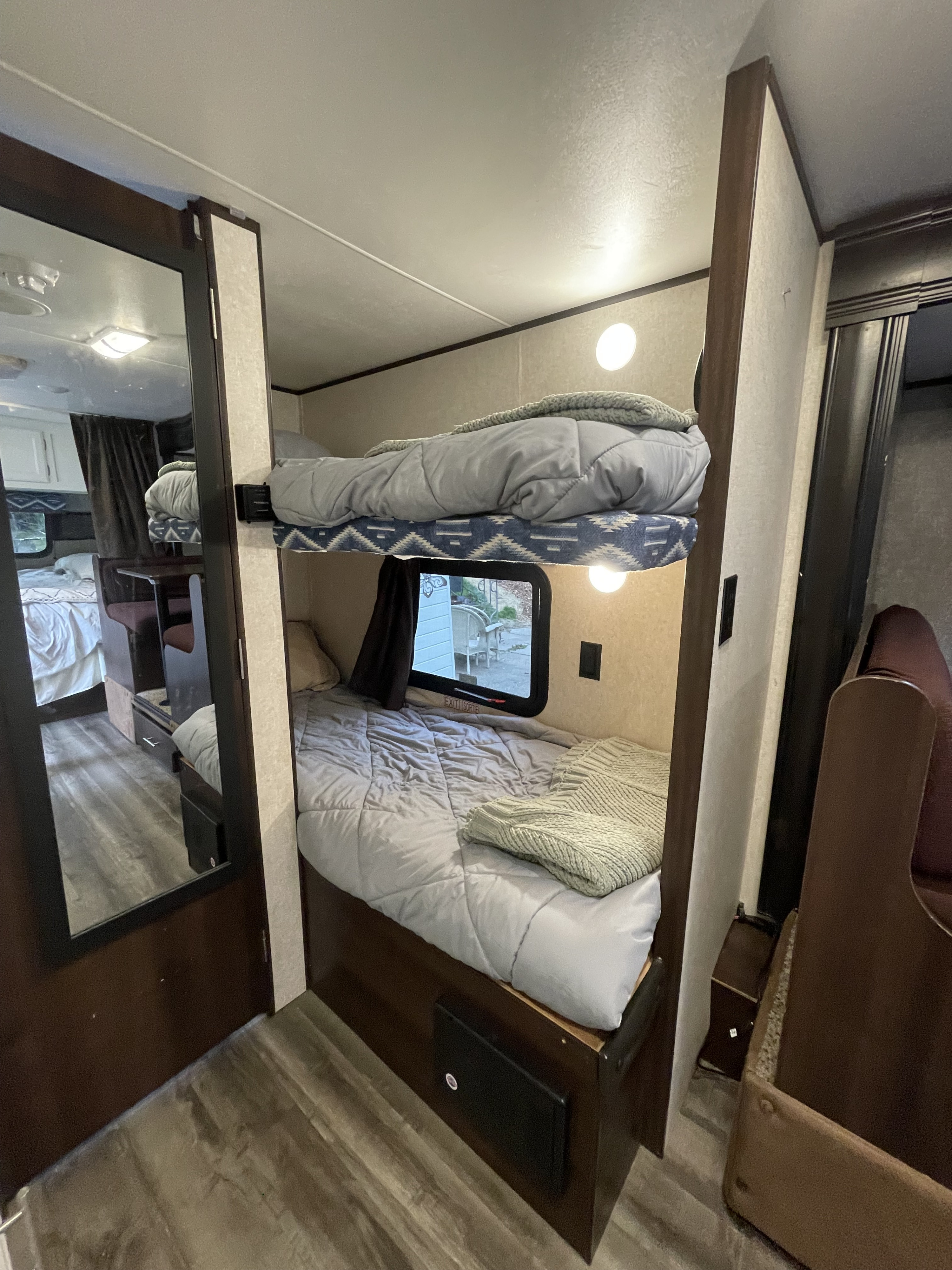 Bright RV rental interior with inviting bunk beds and a mirror reflecting a dining area, providing comfortable sleeping options.. Jayco Jay Flight SLX Baja Edition 2019