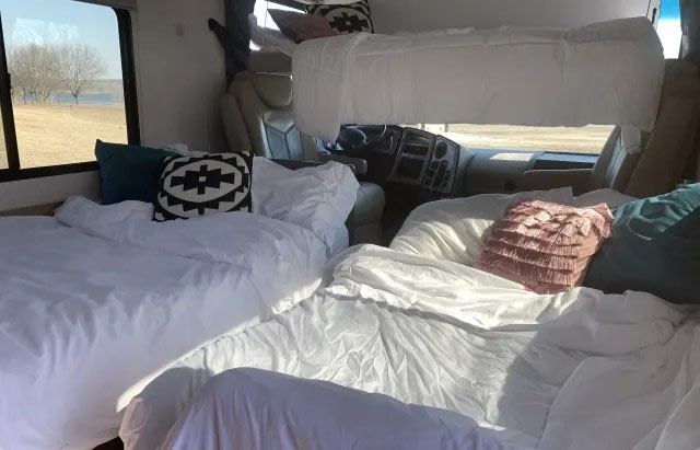 Roomy RV rental bedroom setup with three comfortable beds & scenic lakeside views. Ideal for family road trips.. Coachmen Pursuit 2021