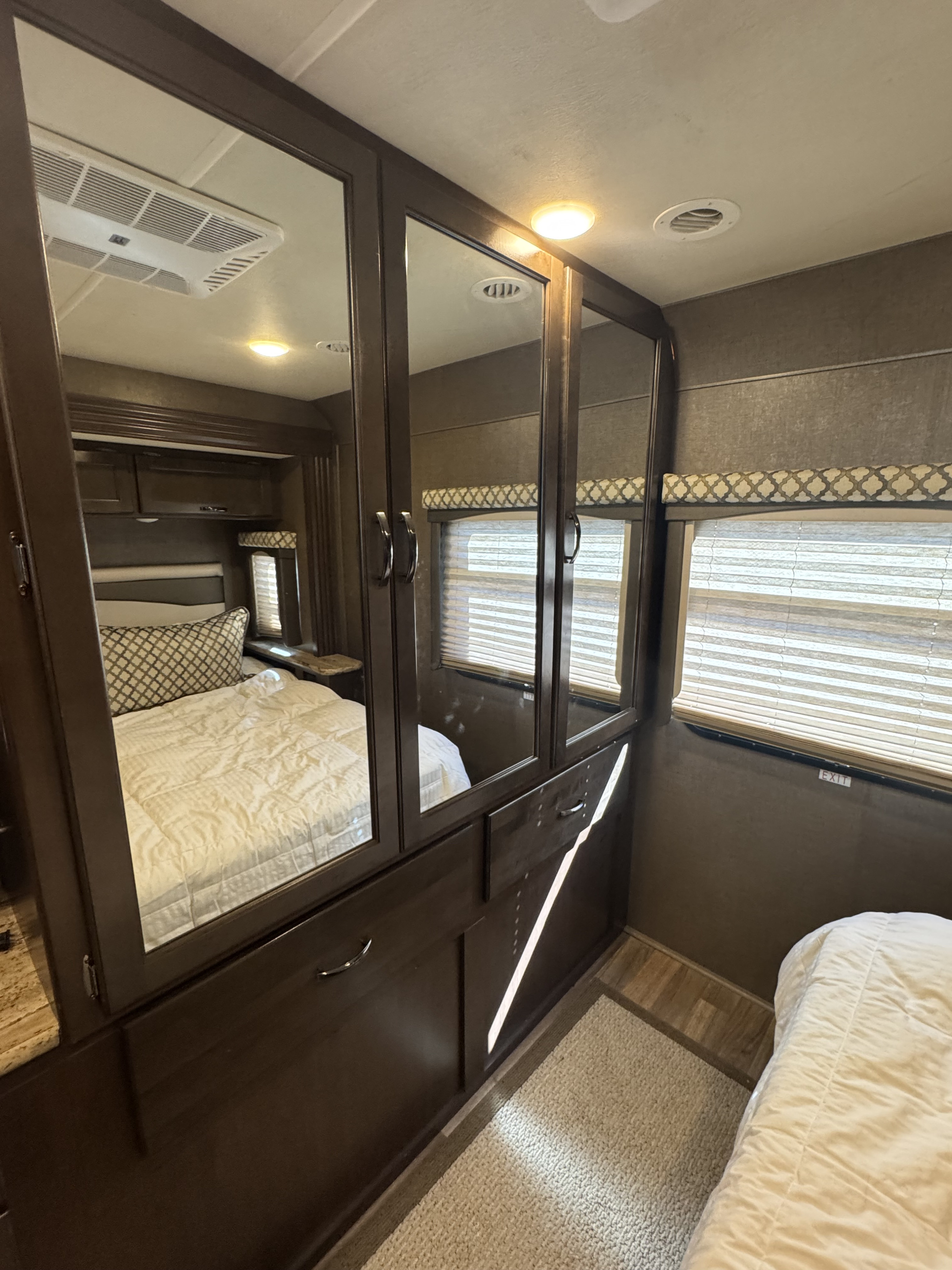 RV rental bedroom featuring a mirrored wardrobe, comfortable bed, overhead AC, and window. Compact & functional space.. Thor A.C.E. 2019