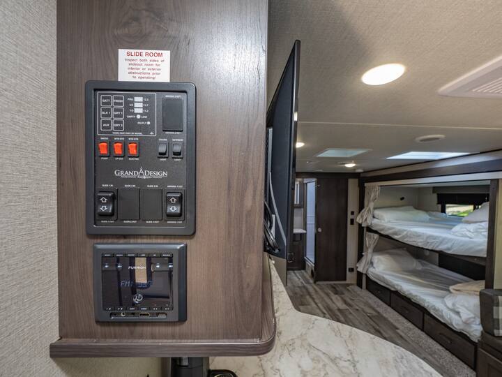 Inside this RV rental: master control panel, Furrion system, swing-out TV, and bunk beds. Perfect for family trips.. Grand Design Transcend Xplor 2023