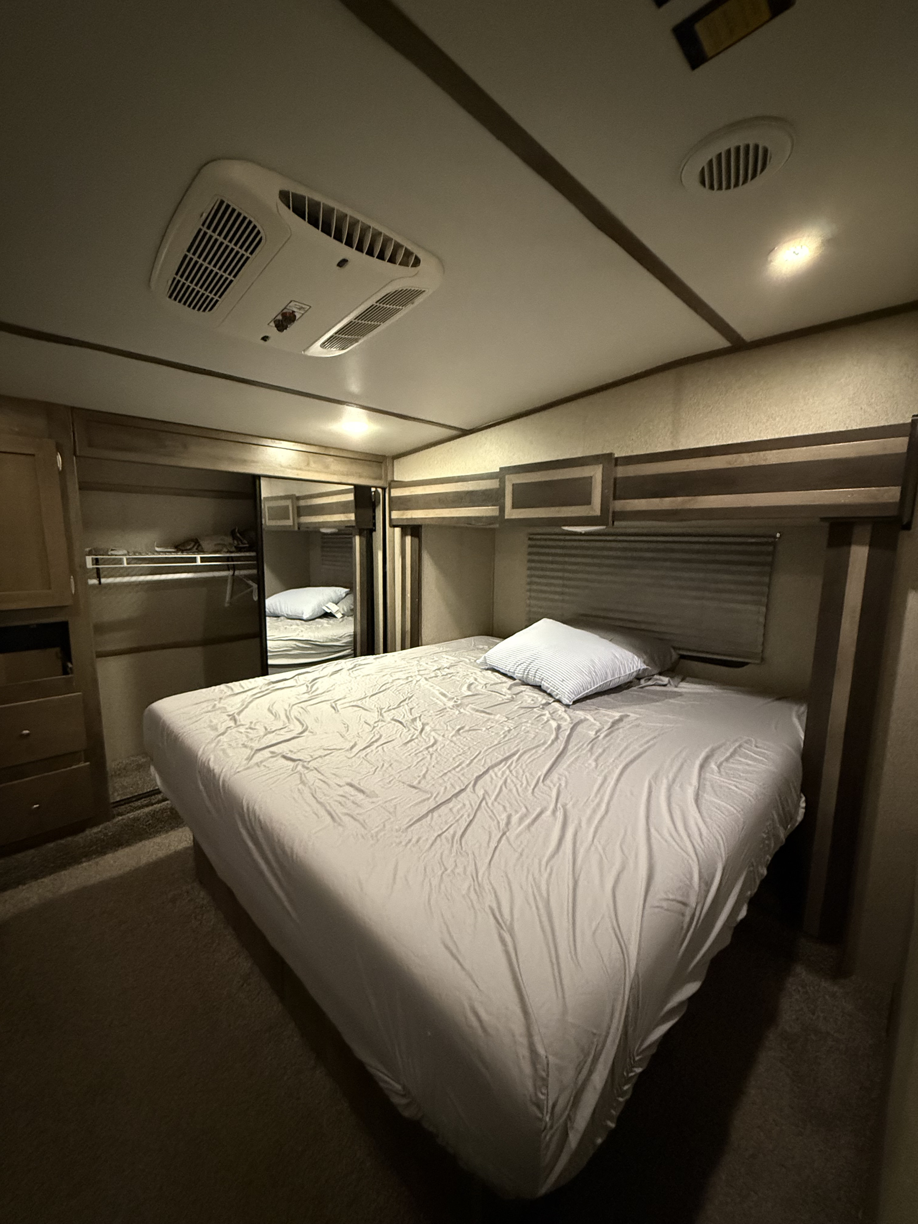 Cozy RV rental sleeping area with a bed, wardrobe, and overhead AC unit for comfortable travel nights.. Keystone Sprinter 2018