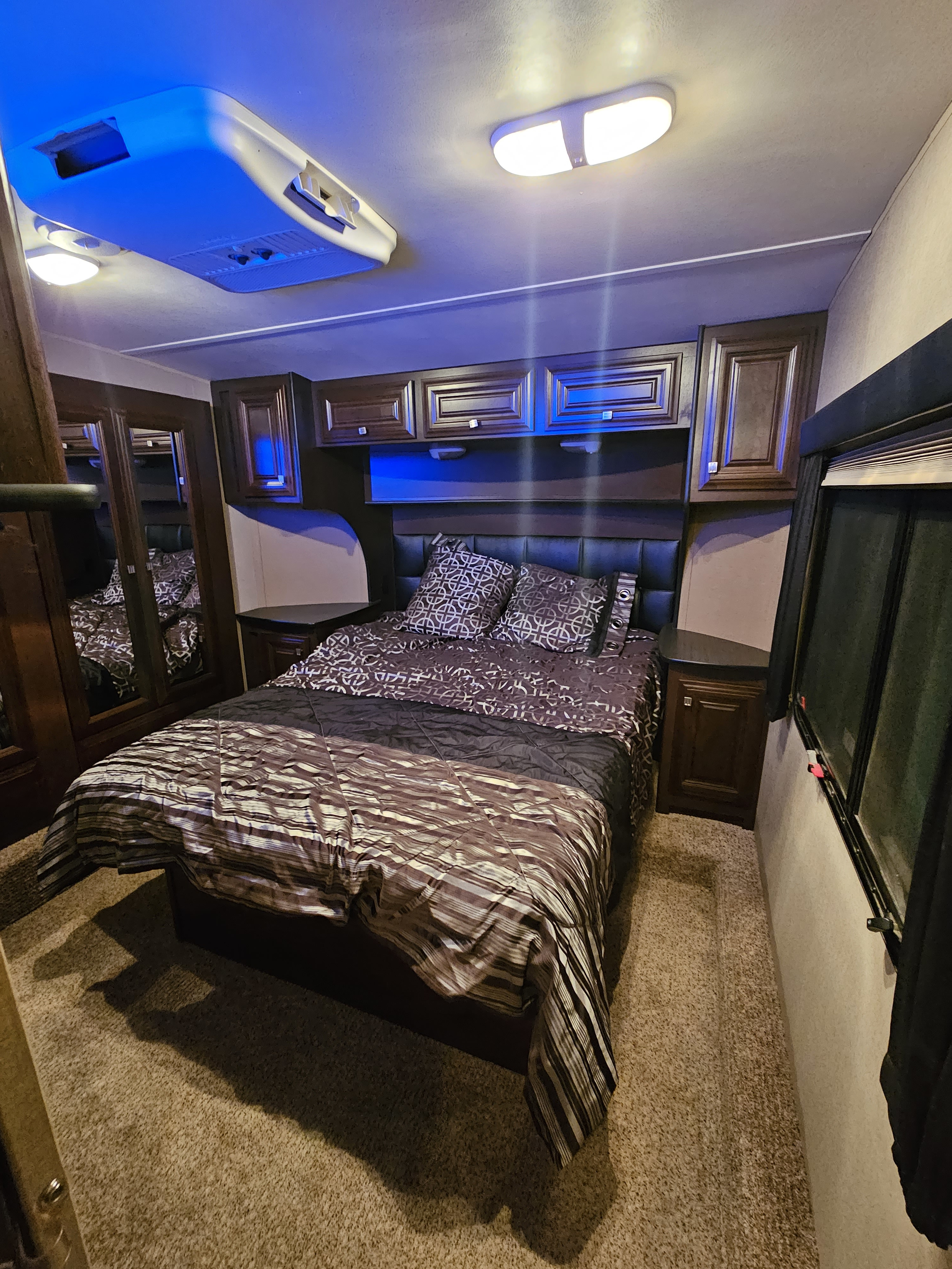 Spacious RV rental bedroom with a comfortable bed, overhead storage, ambient blue lighting, and carpeted floor.. Dutchman Voltage 3605V 2014