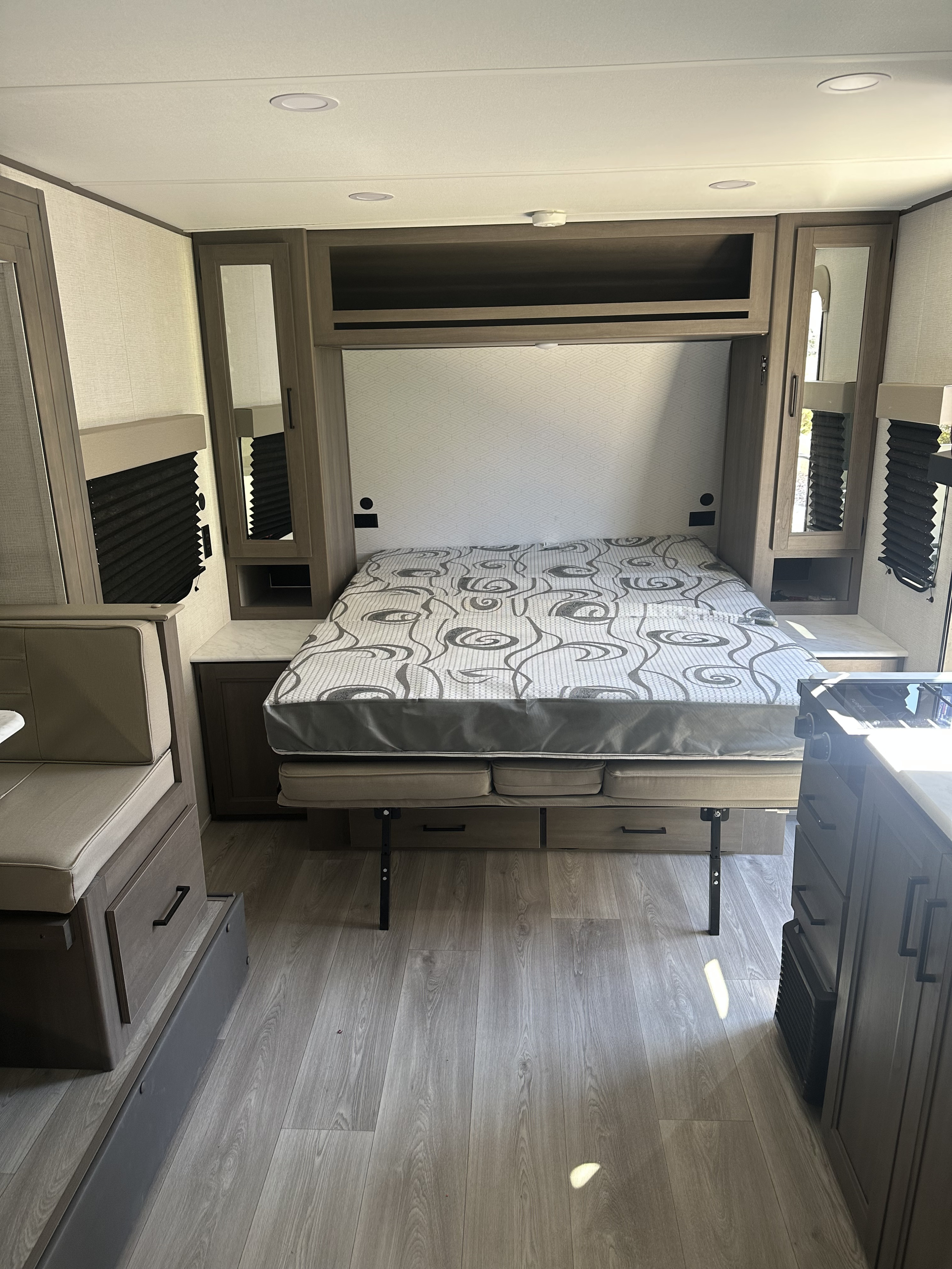 RV rental interior: convertible bed, dinette, and modern fixtures. Neutral tones & wood-look floor for comfort.. Grand Design Transcend One 2025