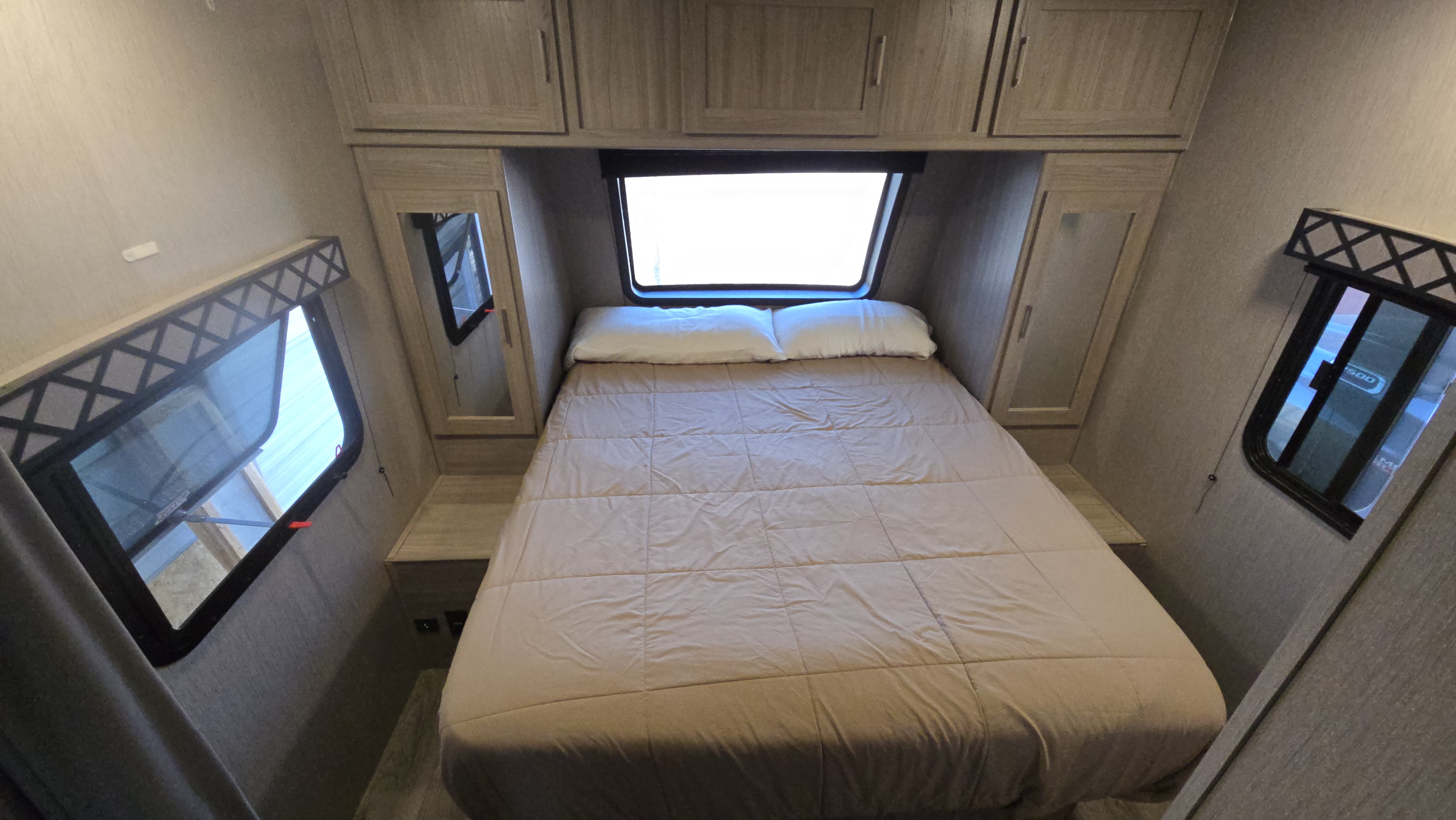 Inside an RV rental bedroom: light bed, overhead cabinets, and windows with valances. A cozy sleeping space for trips.. Forest River Coachmen Freedom Express Ultra Lite 2020