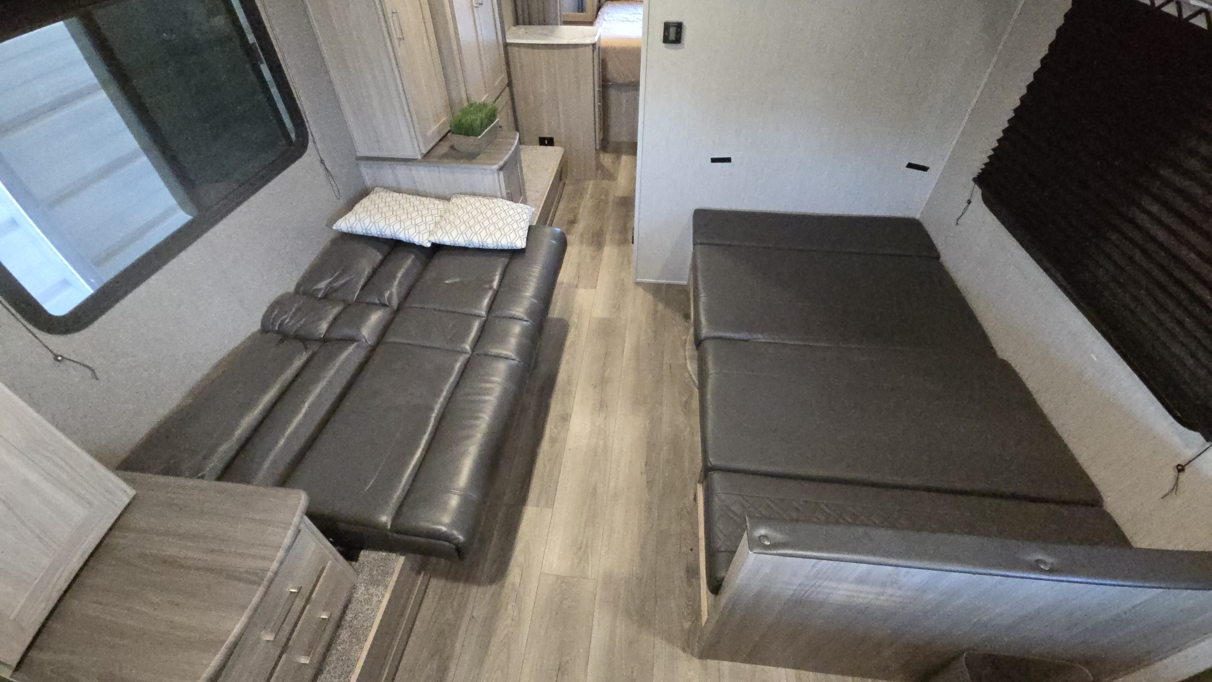 Spacious RV rental interior with two dark sofas/beds and light wood-look flooring, offering versatile living space.. Forest River Coachmen Freedom Express Ultra Lite 2020