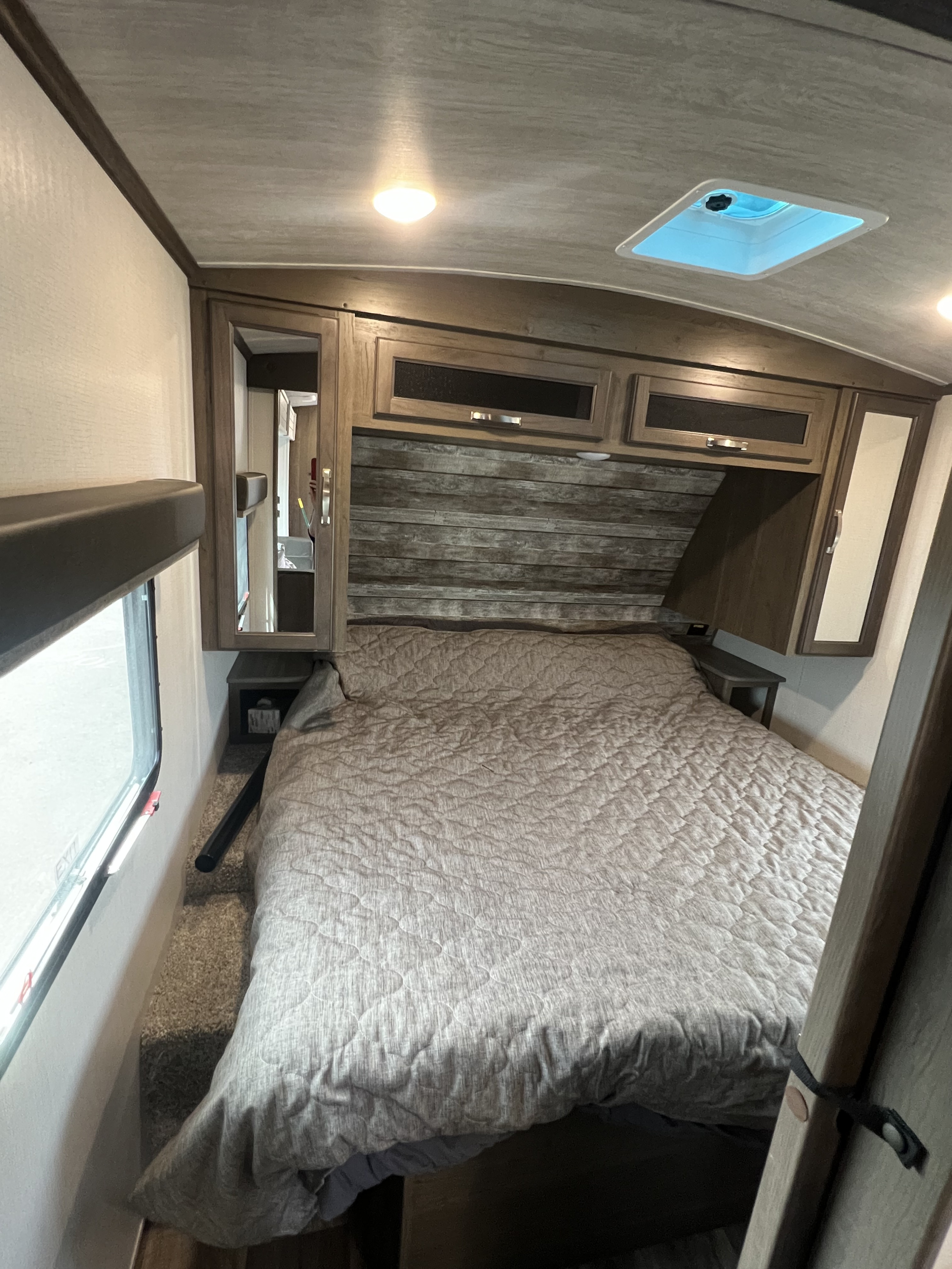 Explore this cozy RV rental bedroom. Features a comfy bed, overhead storage, window, and ceiling vent. Ideal for adventures.. Keystone RV Cougar 2022
