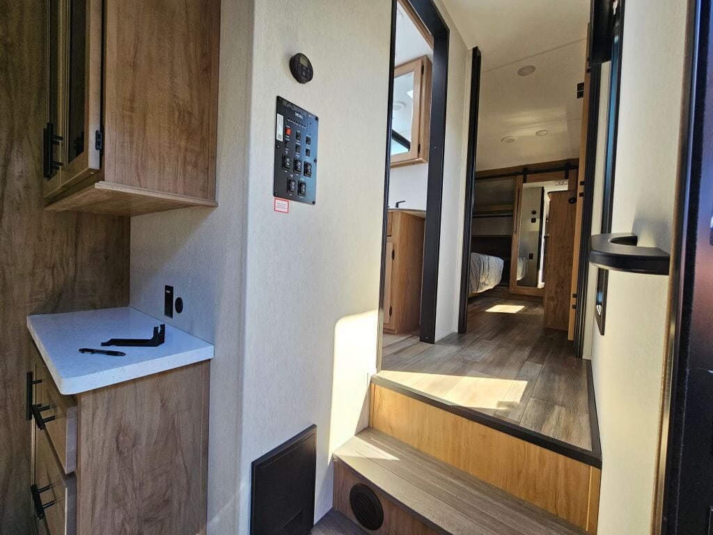 Inside a modern rv rental: notice the control panel, light-wood cabinetry, and open hallway to the bedroom. Comfort for your travels.. Forest River Sabre 38 DBL 2024