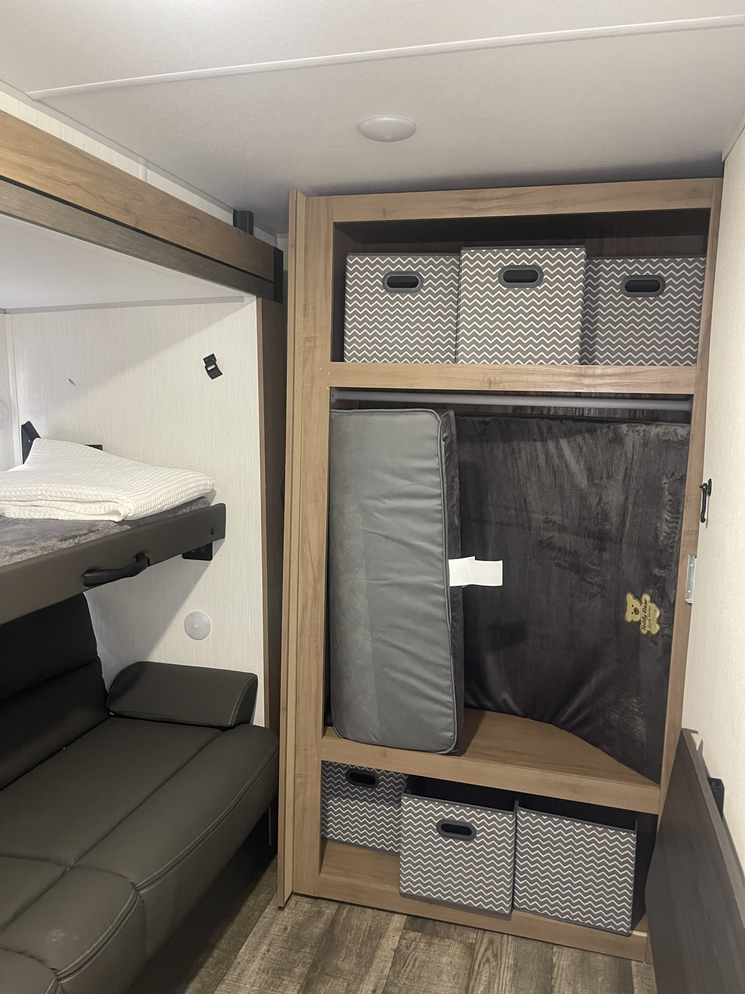 Inside an RV rental: compact living space with bunk beds, sofa, and modular storage bins for an organized interior.. Forest River Campsite reserve 27MR 2025