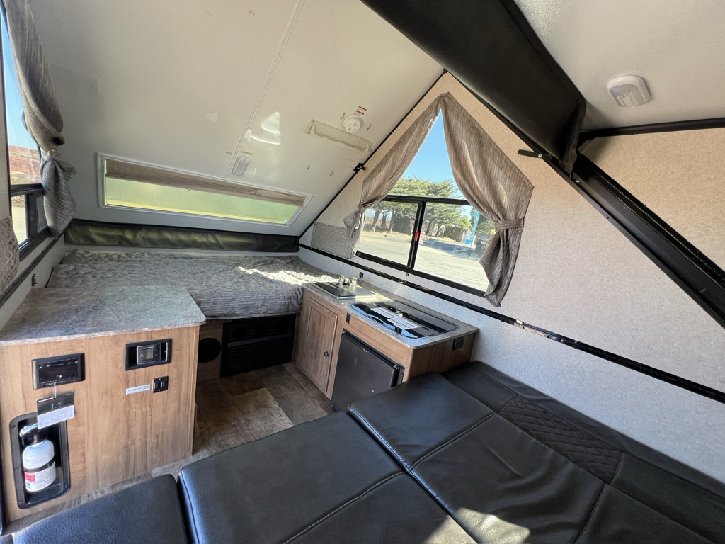 Compact RV rental interior: cozy A-frame camper with bed, kitchen, and seating area.. Forest River A122BH 2018