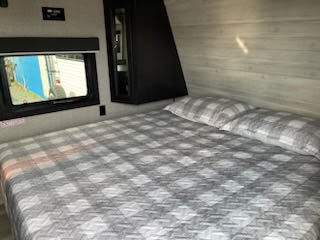 RV rental interior: This cozy RV bedroom features a queen bed with plaid bedding, a window, and built-in storage.. Jayco Jay Flight 2022