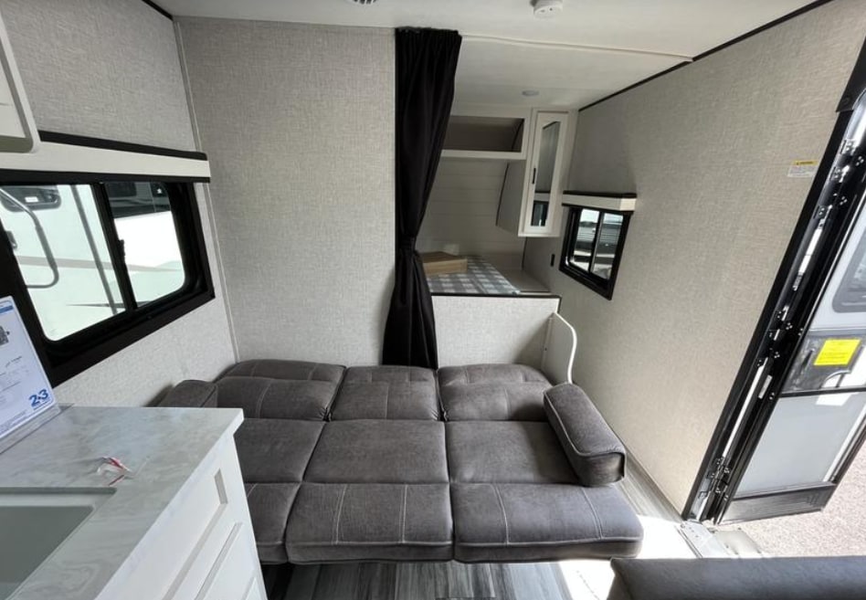 Cozy RV rental interior with a versatile sofa bed, kitchenette, and private sleeping nook, ideal for compact living.. Jayco Jay Flight 2022