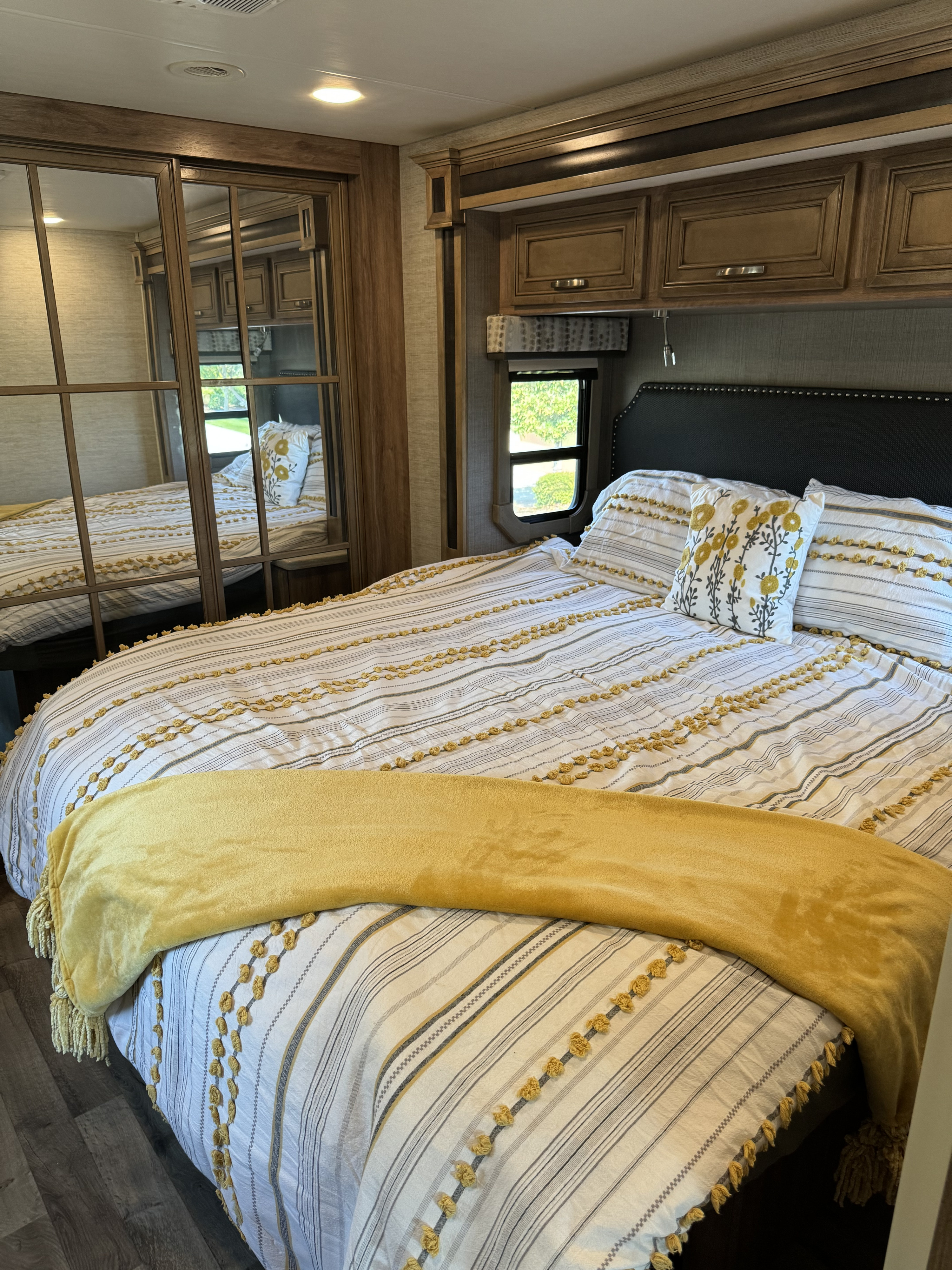 Comfortable RV rental bedroom featuring a striped bed with yellow accents, a cozy throw, and a mirrored closet.. Jayco Precept Prestige 2021